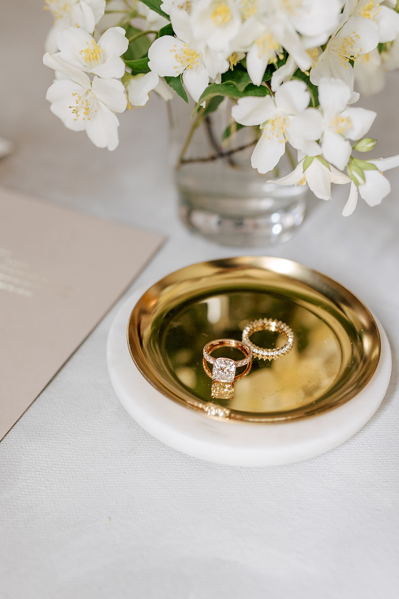 Gold ring dish with rings and white flowers in a vase | Photo by NYC Wedding Photographer Hope Helmuth 