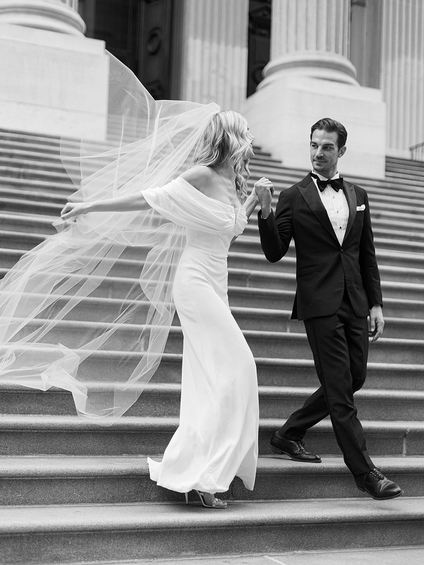 Black and white photo of bride and groom walking down stairs | Photo by Hope Helmuth Photography