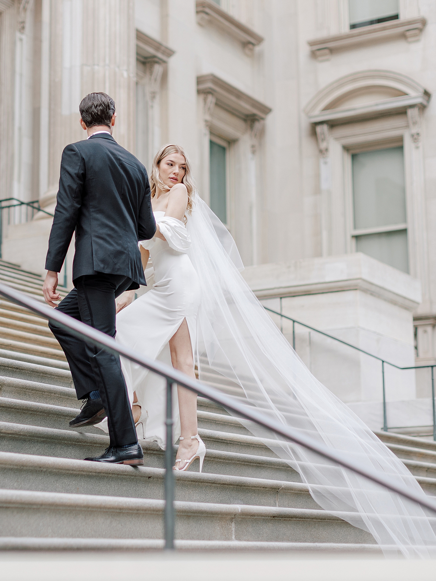 Groom and bride in veil walking up the stairs at The Ritz | Photo by NYC Wedding Photographer Hope Helmuth