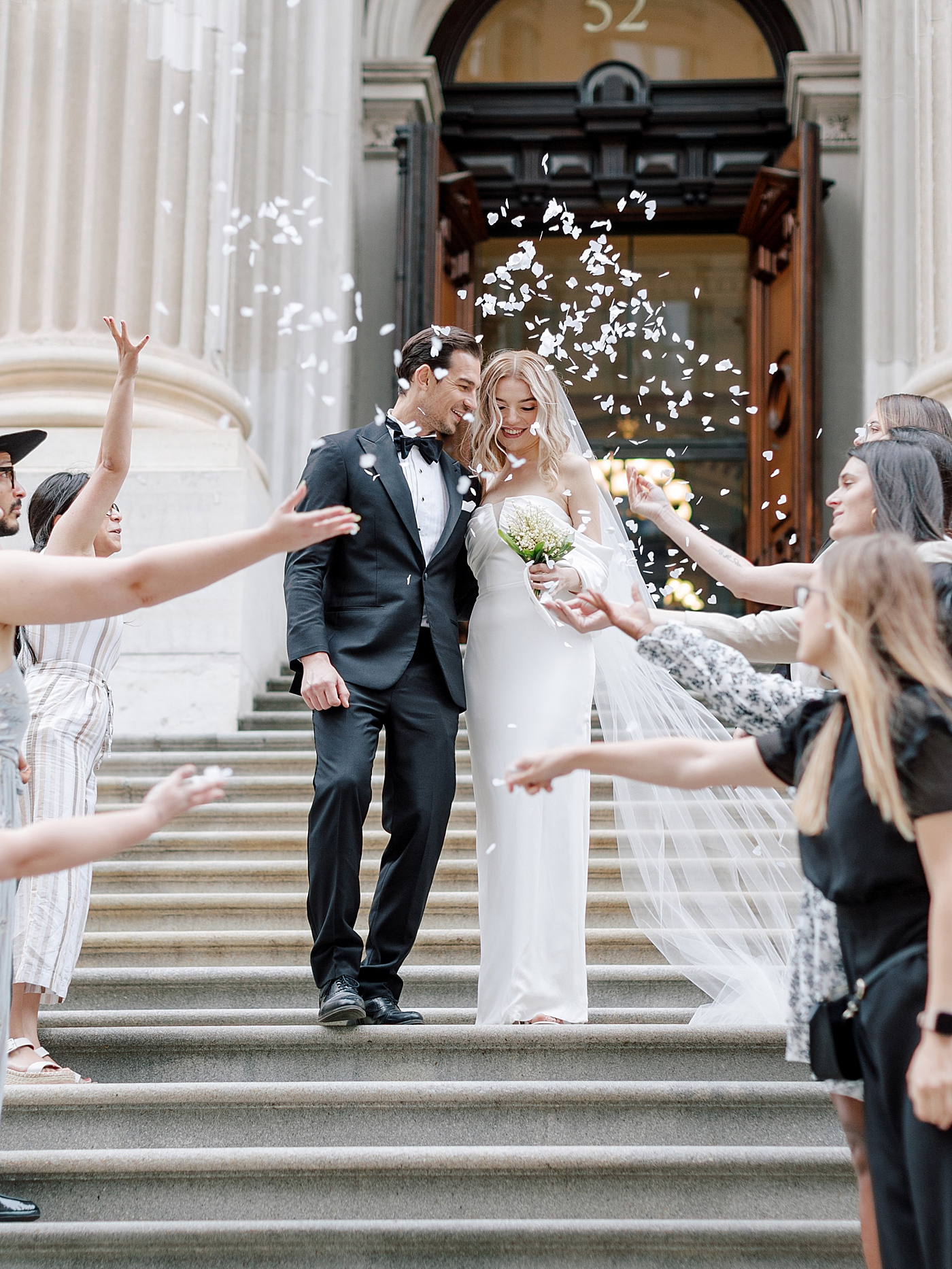 Bride and groom walking down stairs through confetti | Photo by Hope Helmuth Photography