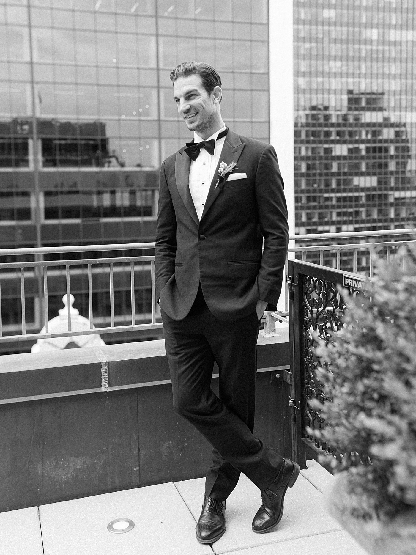 Groom in a suit on a balcony overlooking NYC | Photo by Hope Helmuth Photography