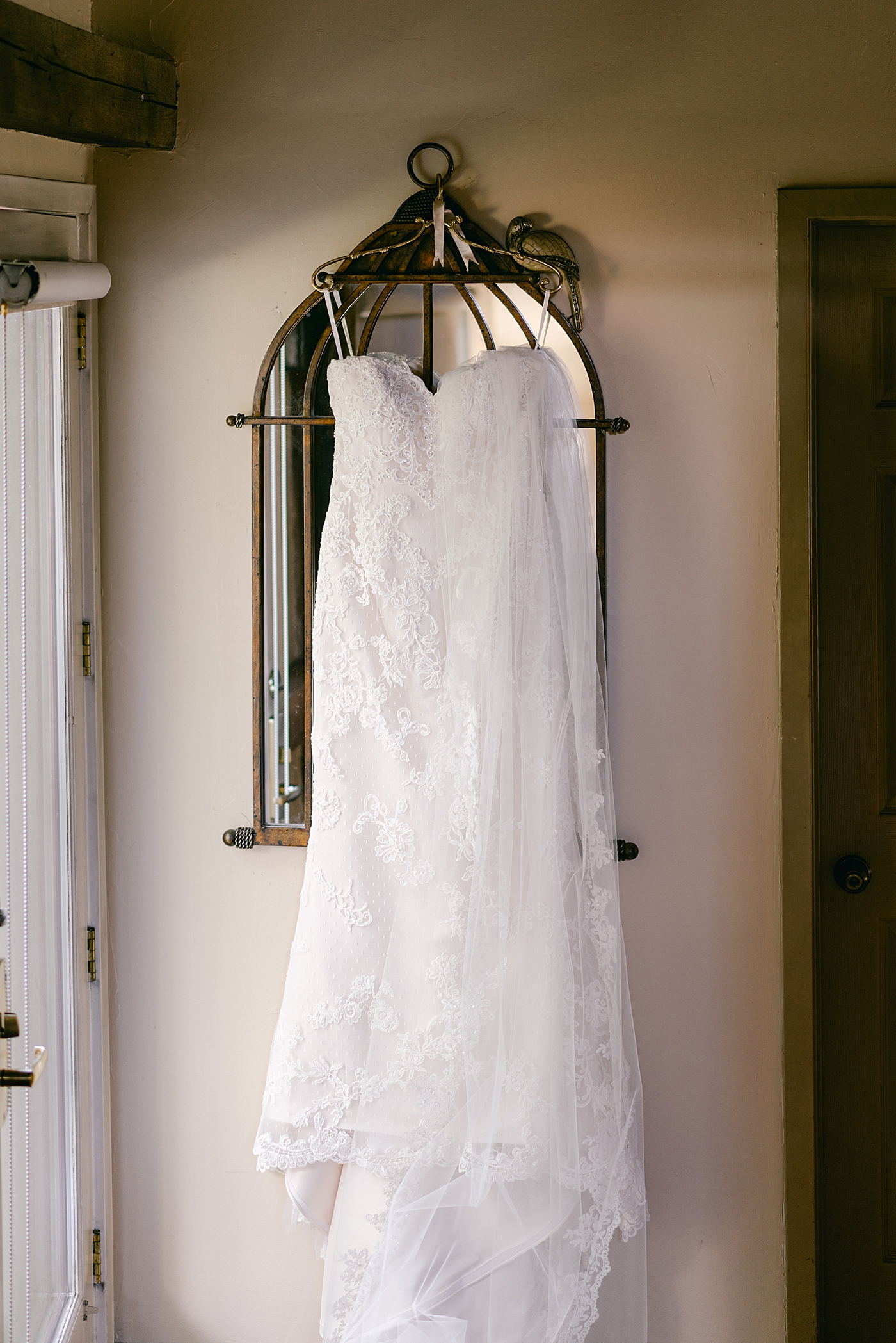 Lace bridal gown hanging on a mirror | Photo by Hope Helmuth Photography