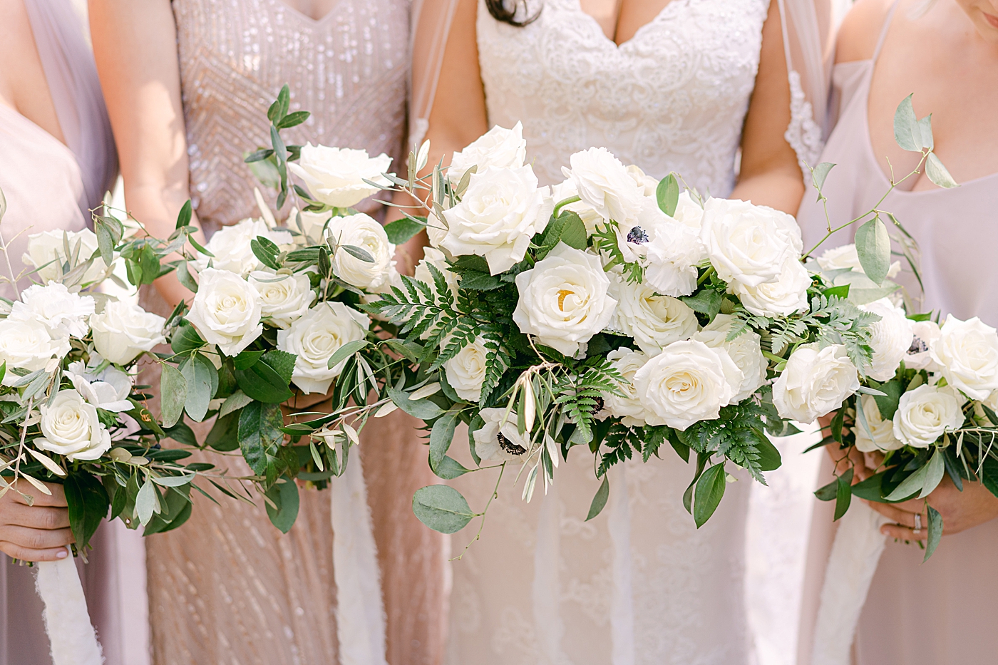 Bouquets in a line held by bridesmaids | Photo by Hope Helmuth Photography