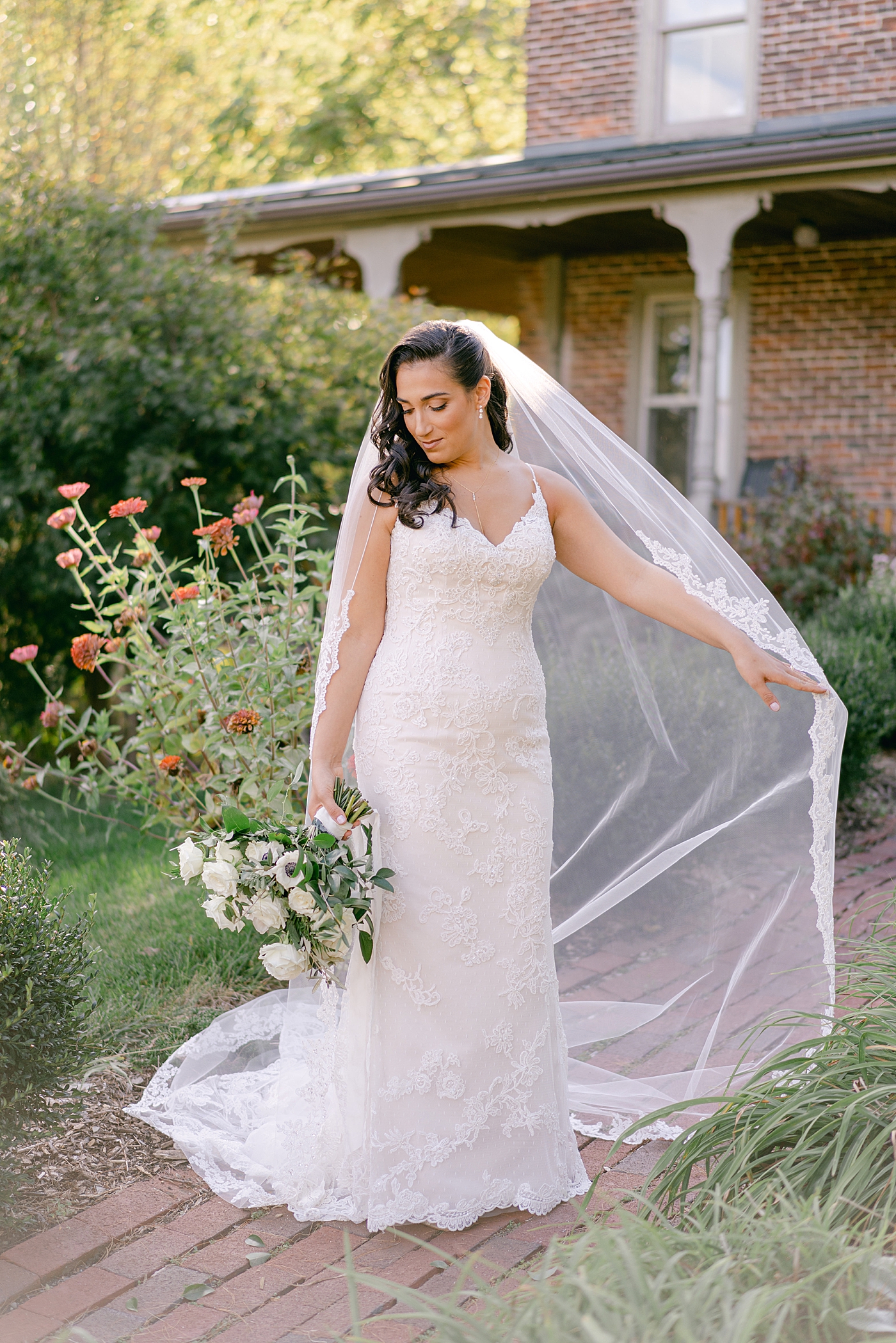 Bride holding her veil and bouquet | Photo by Hope Helmuth Photography