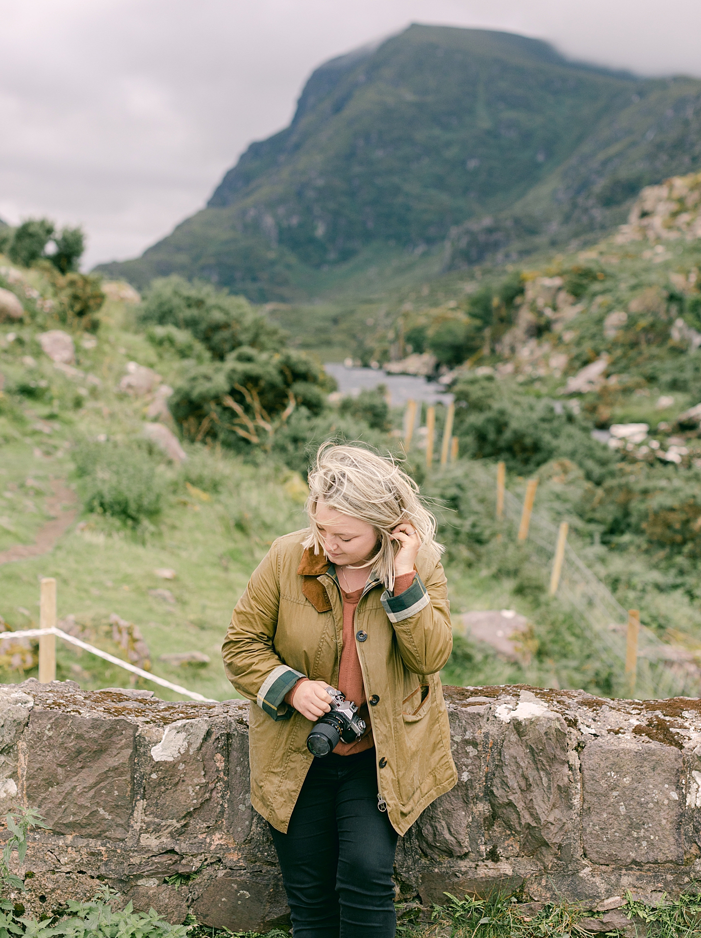 Woman in a brown jacket holding a camera | Photo by Destination Wedding Photographer Hope Helmuth