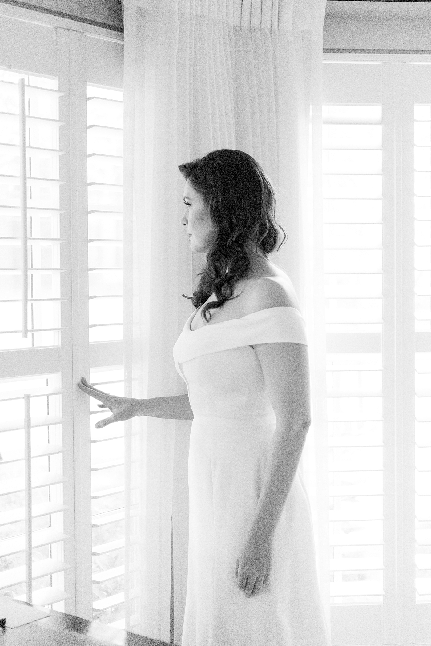 Black and white image of bride looking out the window | Photo by Hope Helmuth Photography