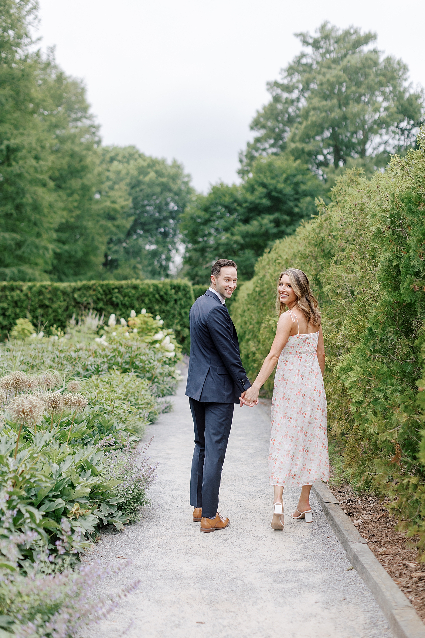 Couple holding hands walking through Longwood Garden | Photo by Hope Helmuth Photography