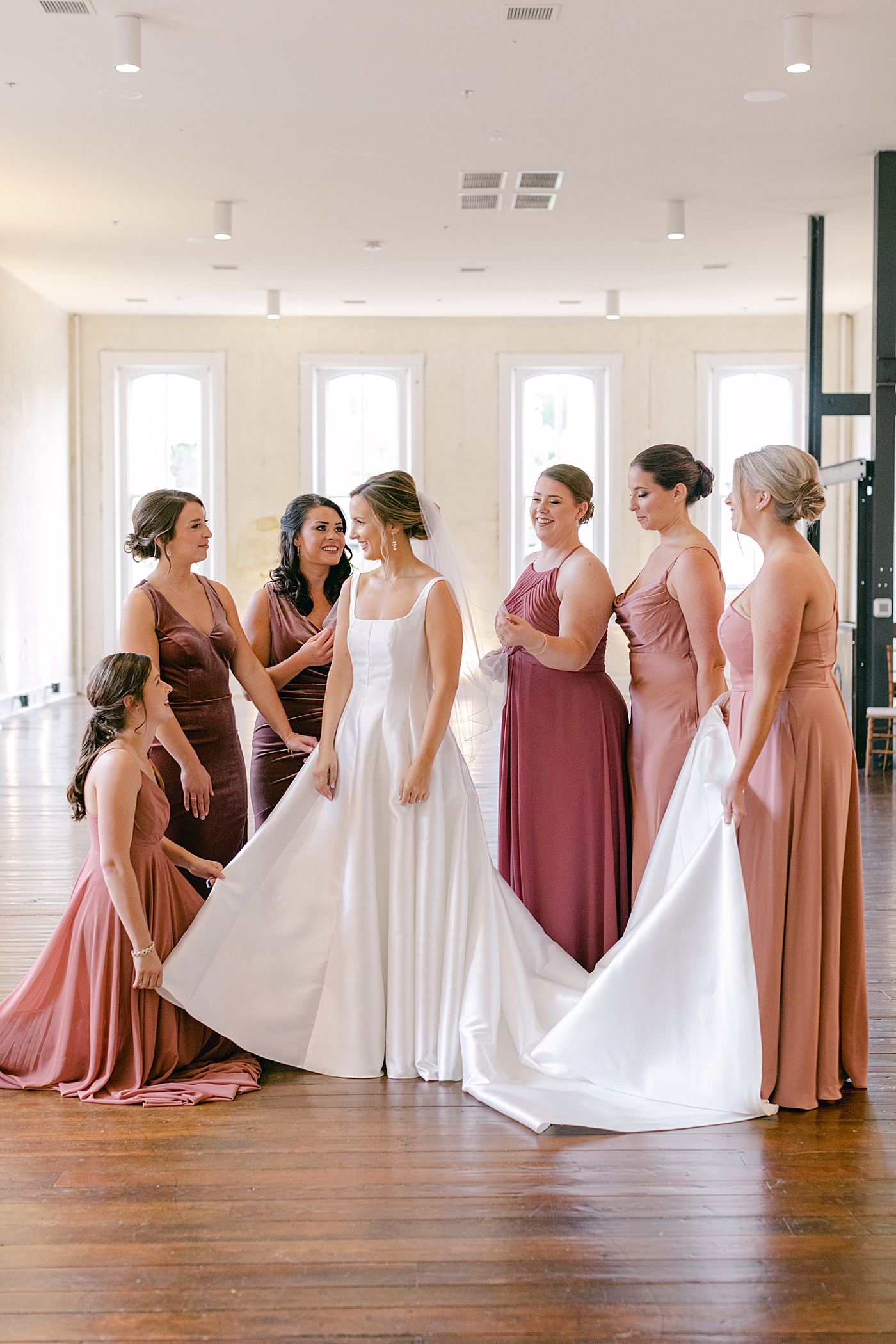 Bridesmaids helping bride with her dress | Photo by Hope Helmuth Photography