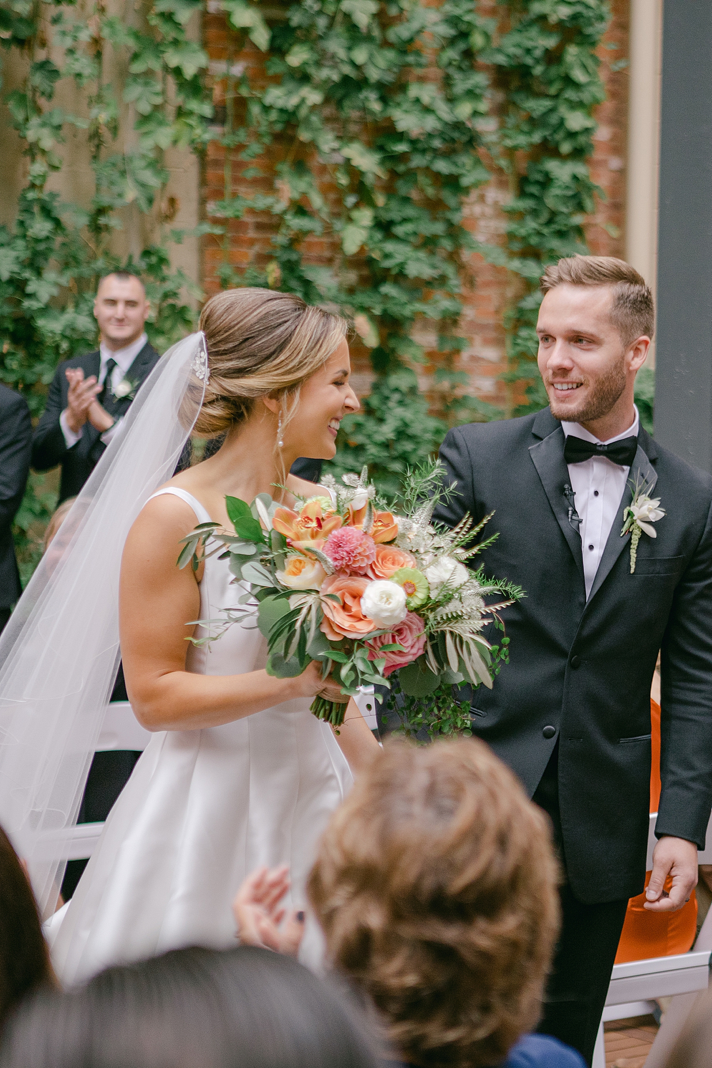 Bride and groom smiling as they leave their wedding | Photo by Hope Helmuth Photography