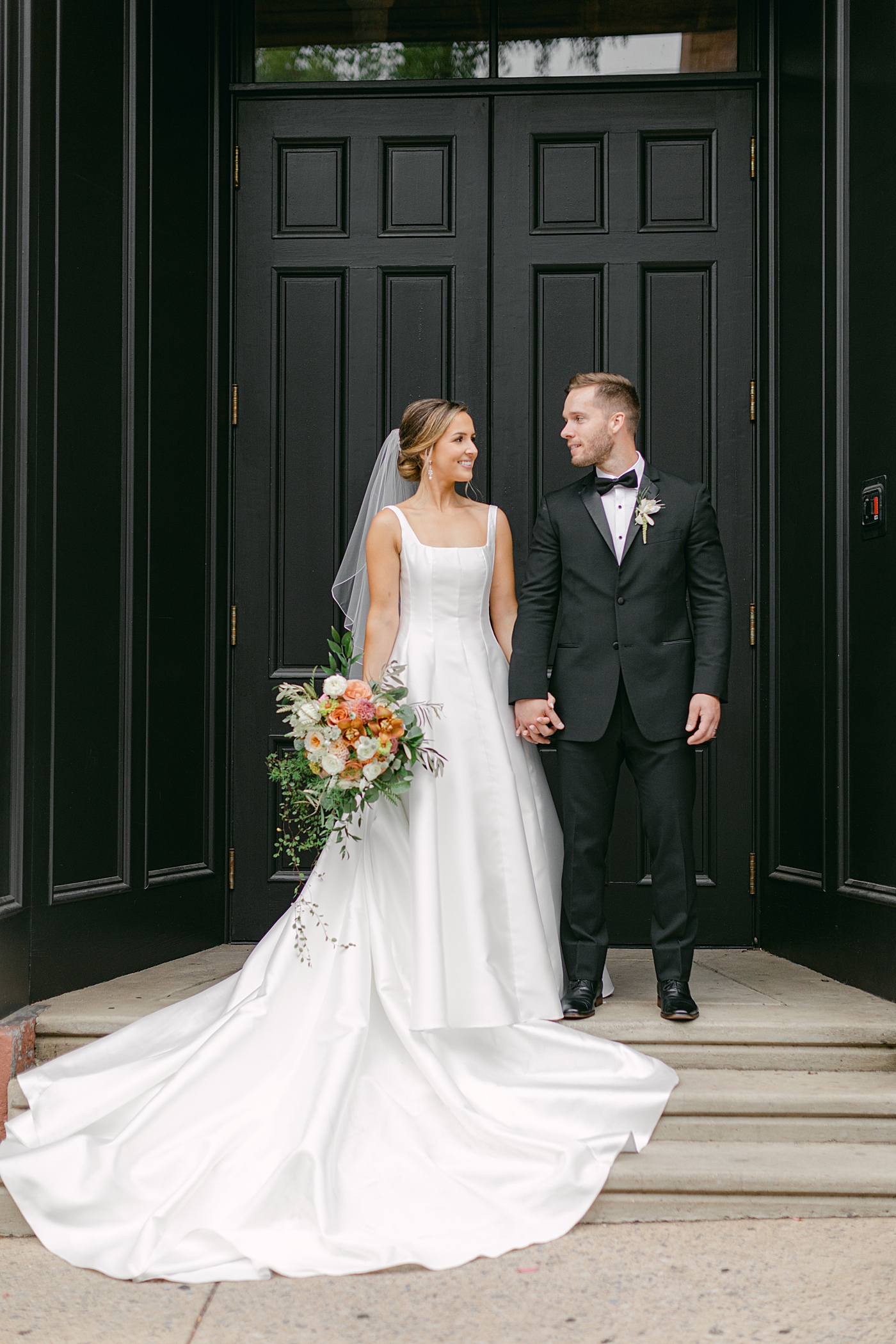 Bride and groom holding hands in a black doorway | Photo by Hope Helmuth Photography