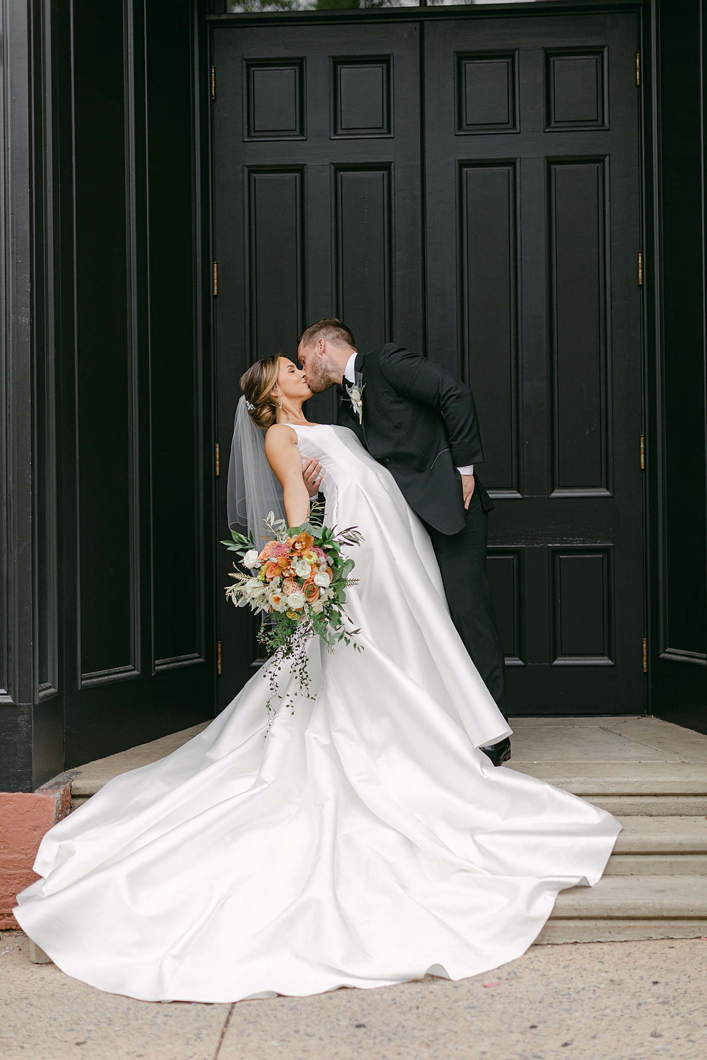 Bride and groom kissing in a black doorway | Photo by Hope Helmuth Photography