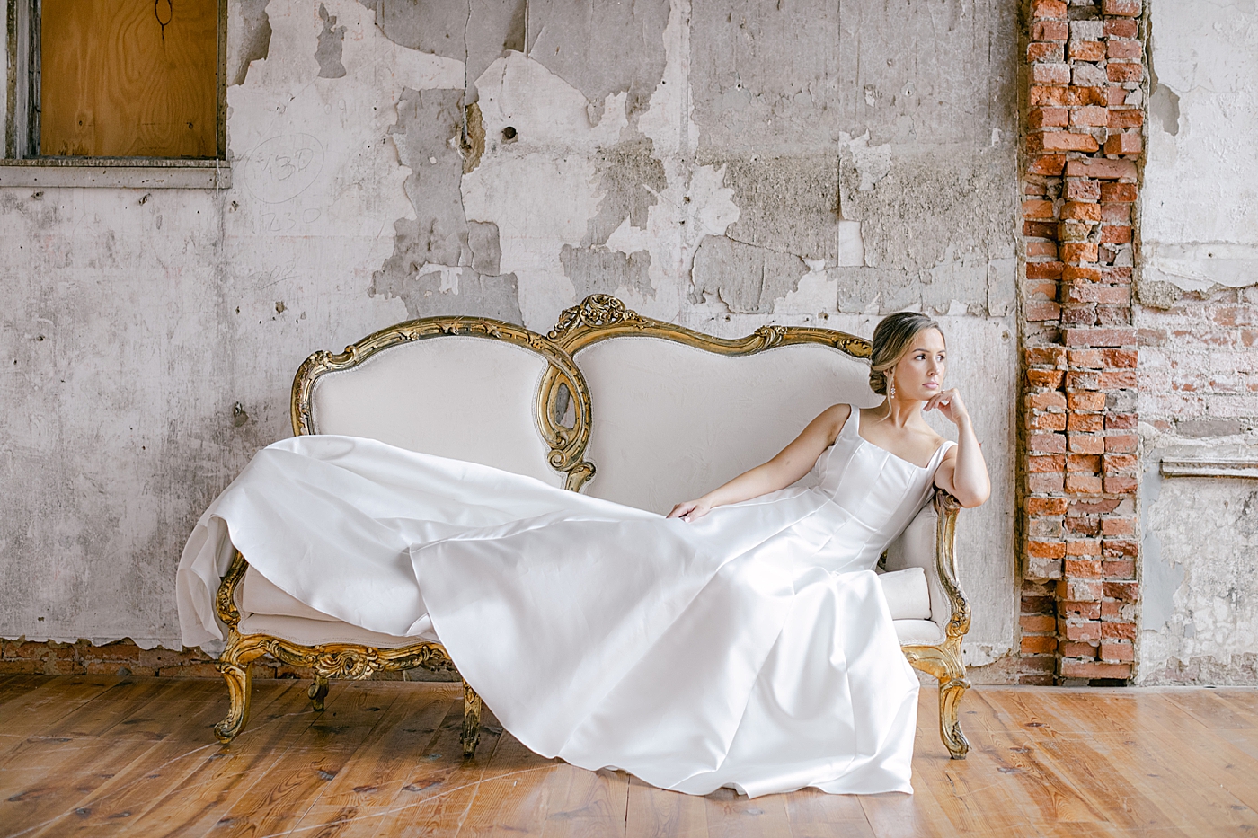Bride in a wedding dress sitting on a sofa | Photo by Hope Helmuth Photography