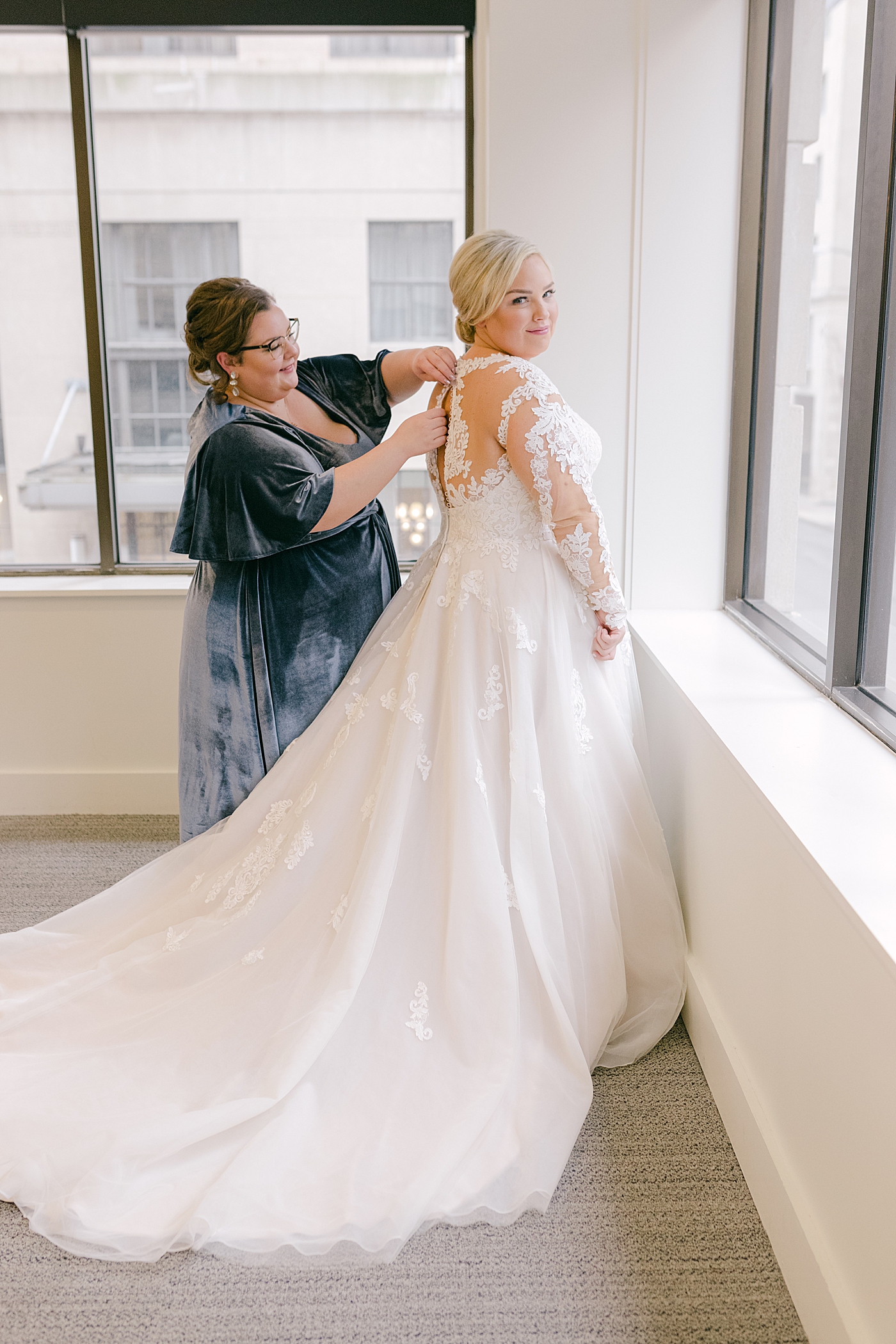 Bride being buttoned into her dress | Photo by Hope Helmuth Photography