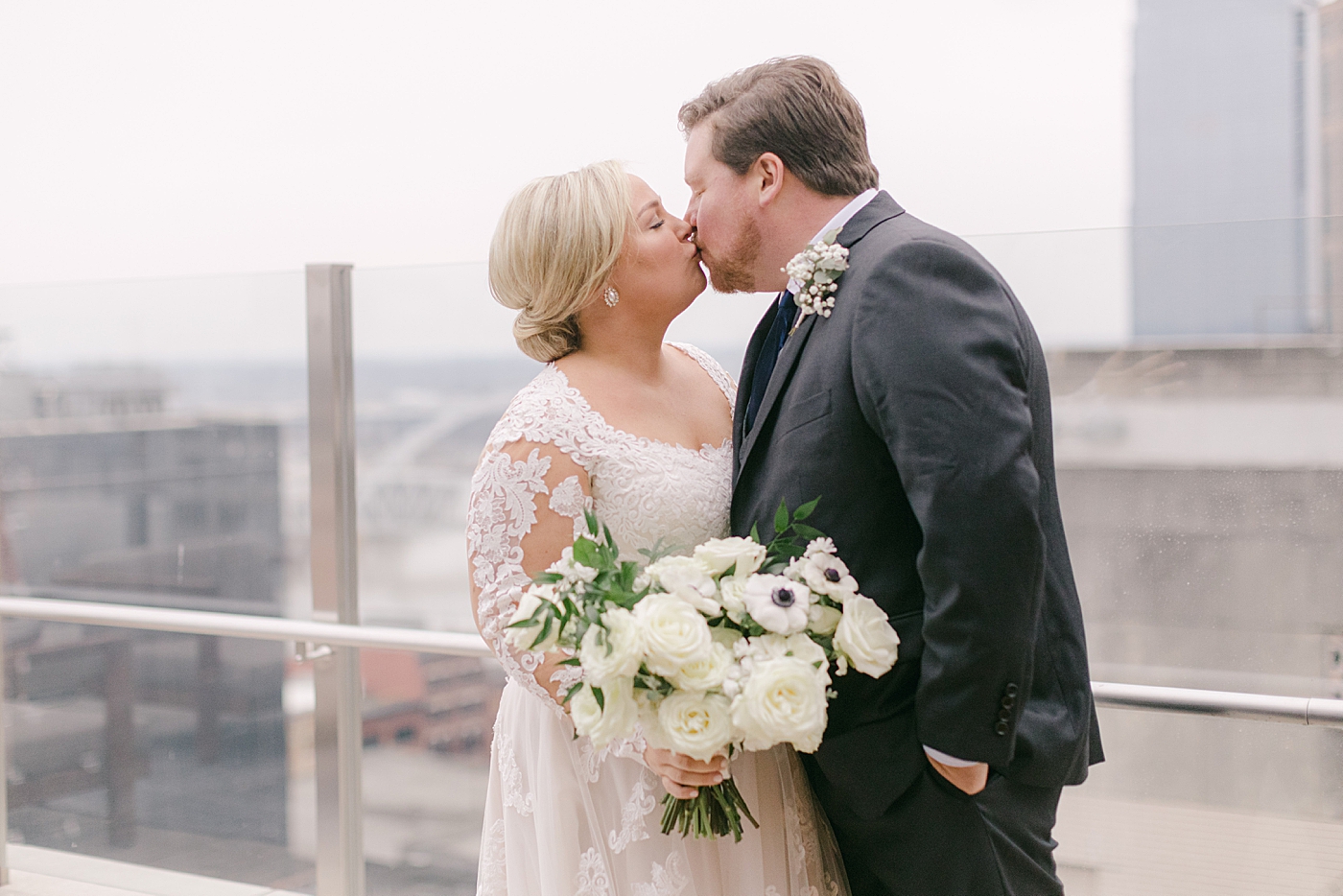Bride and groom kissing on a rooftop | Photo by Hope Helmuth Photography