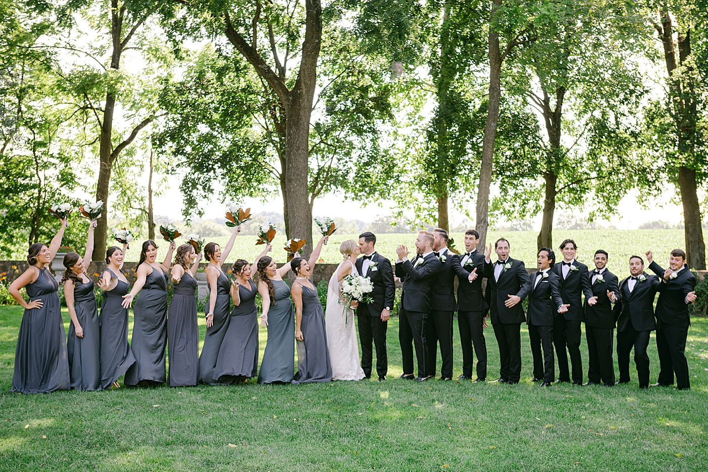 Bride and groom kissing while wedding party cheers | Image by Hope Helmuth Photography