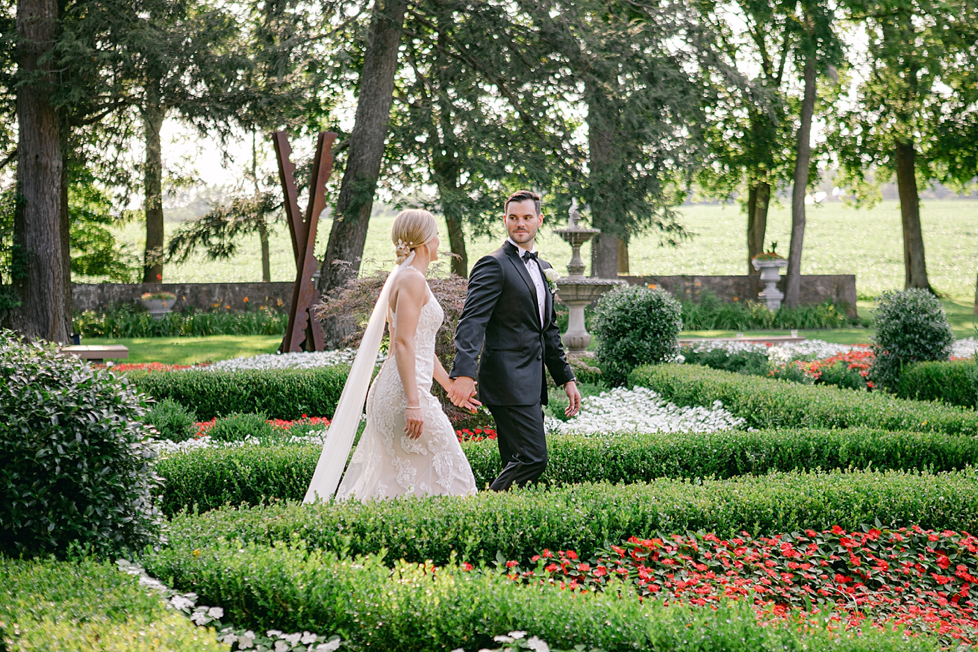 Bride and groom walking through a garden holding hands | Image by Hope Helmuth Photography