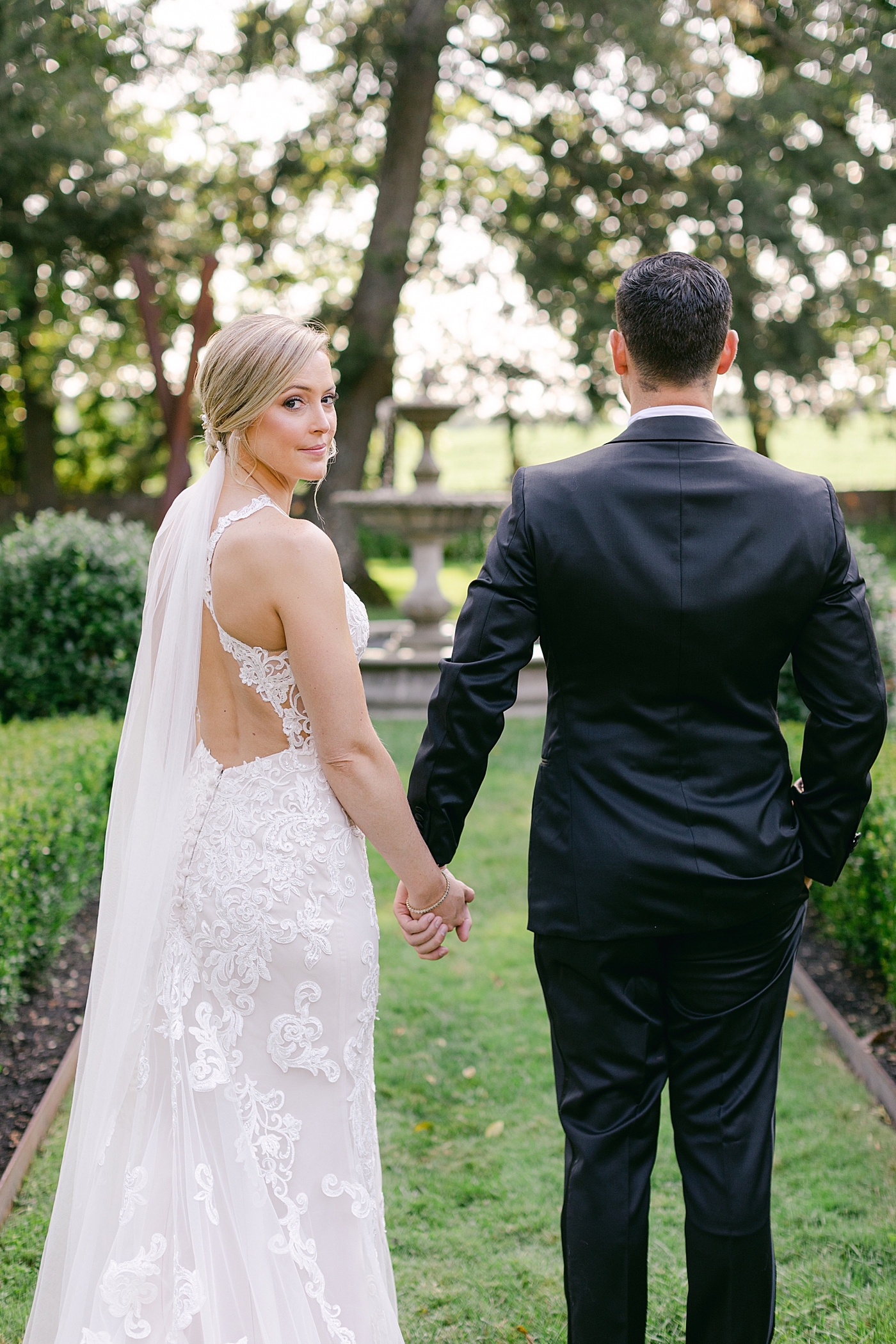 Bride looking over her shoulder holding grooms hand | Image by Hope Helmuth Photography