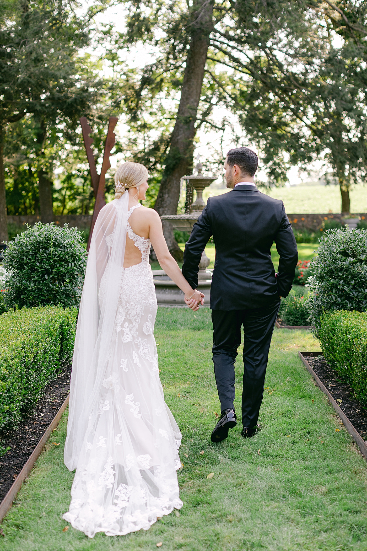 Bride and groom walking through a garden during Hotel du Village Wedding | Image by Hope Helmuth Photography