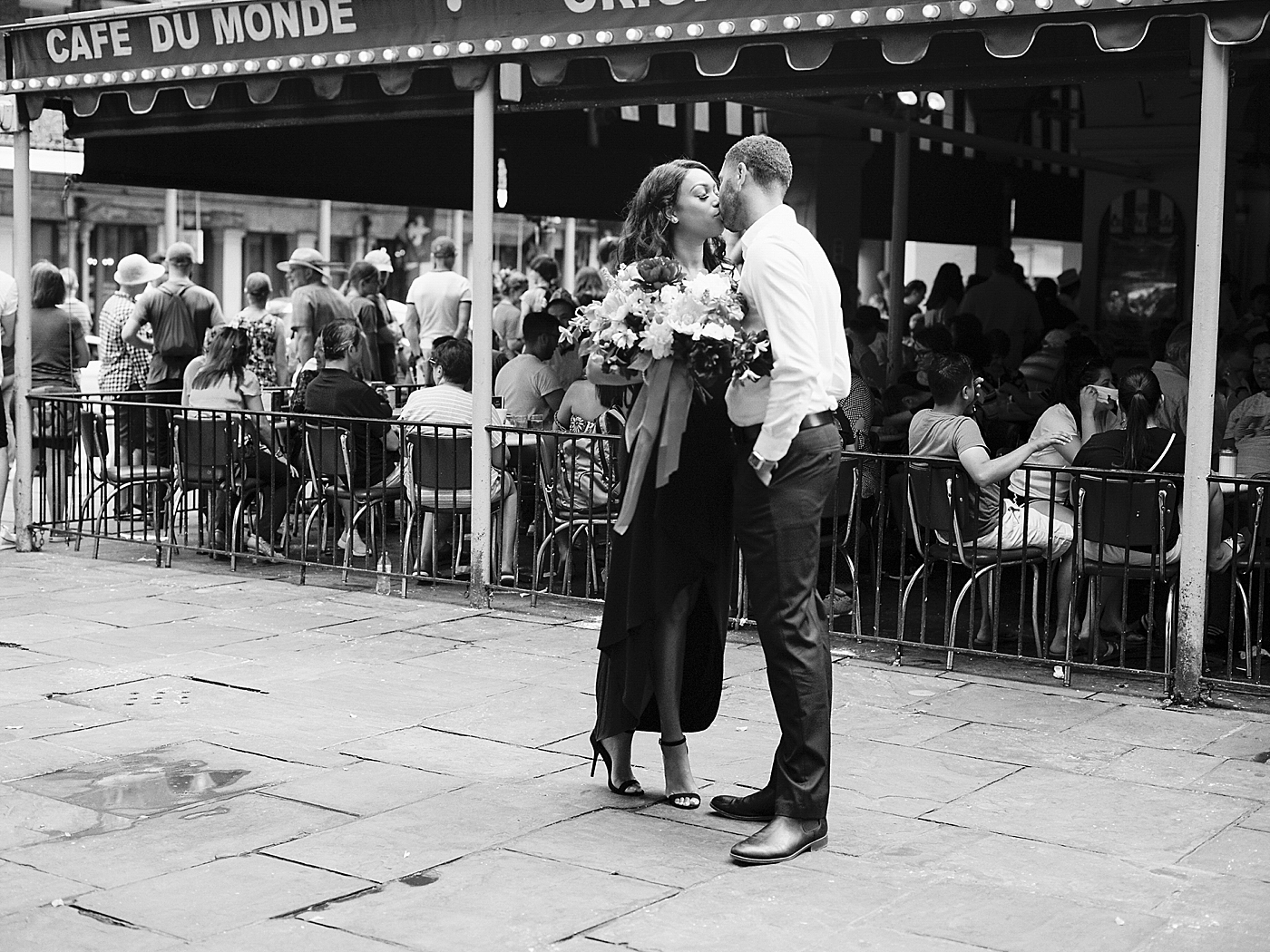 Black and white image of couple kissing in front of Cafe Du Monde | Photo by Hope Helmuth Photography