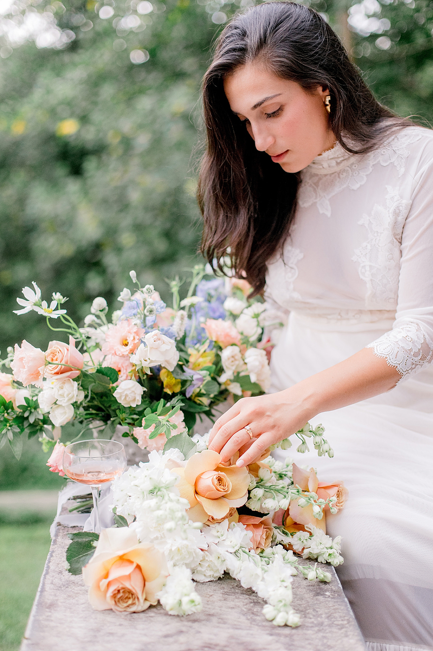 Bride in a white dress with wedding flowers in peaches and white | Image by Hope Helmuth Photography