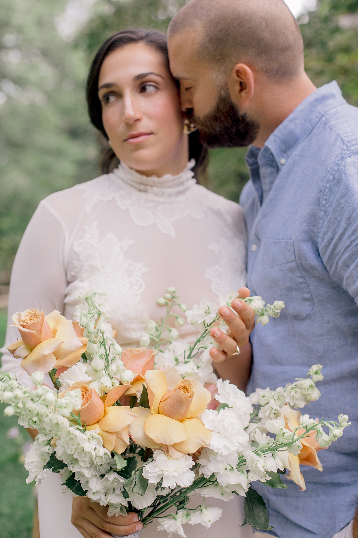 Groom nuzzling brides cheeks while she holds a peach colored bouquet | Image by Hope Helmuth Photography