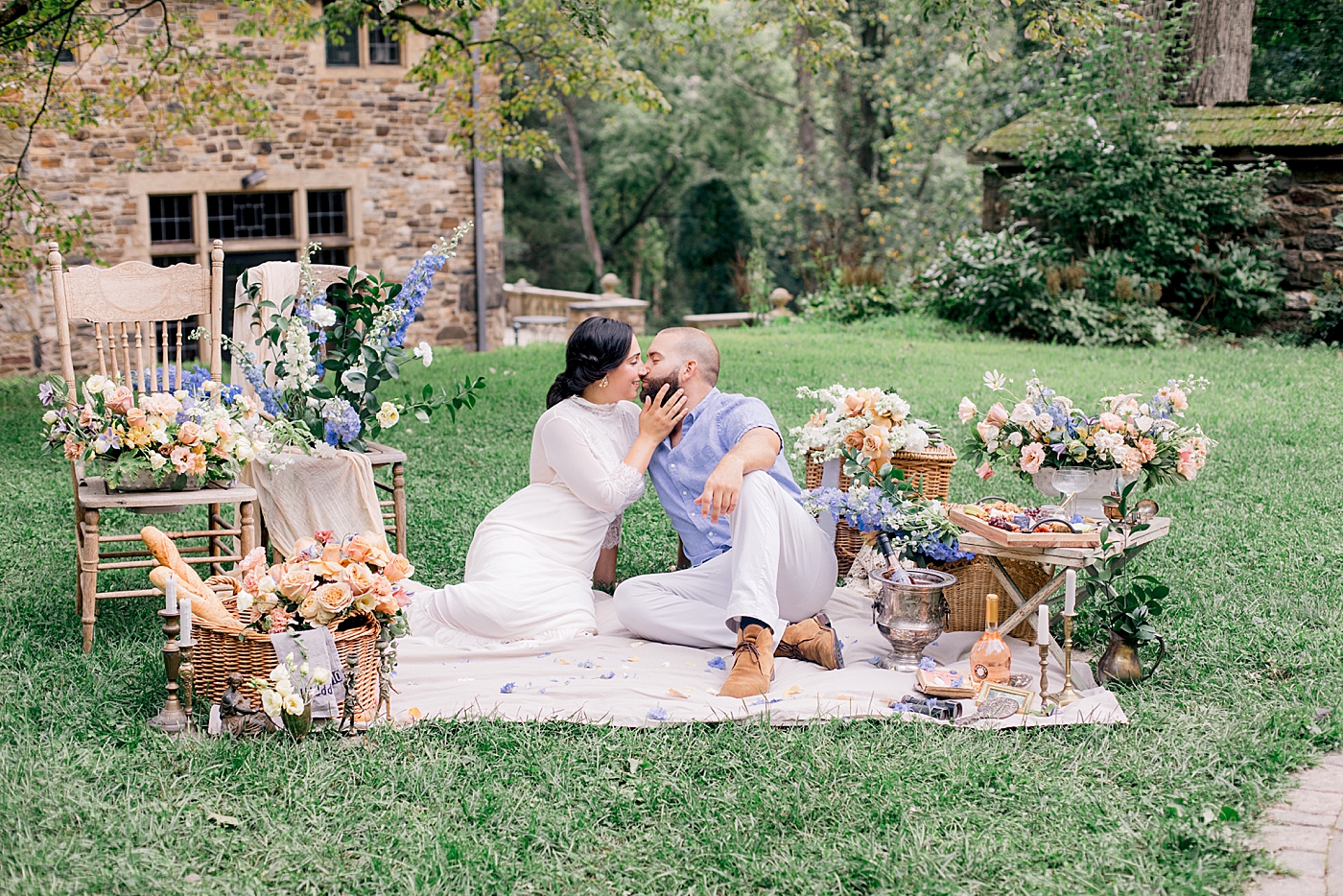 Bride and groom sitting on a picnic blanket surrounded by florals | Image by Hope Helmuth Photography