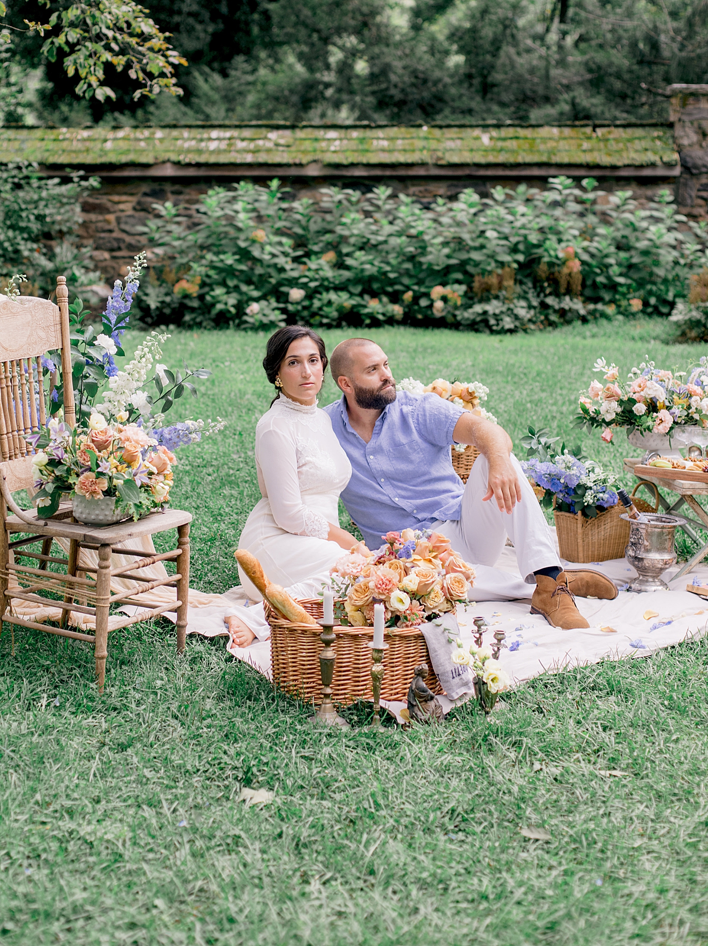 Bride and groom sitting on a picnic blanket surrounded by flowers | Image by Hope Helmuth Photography