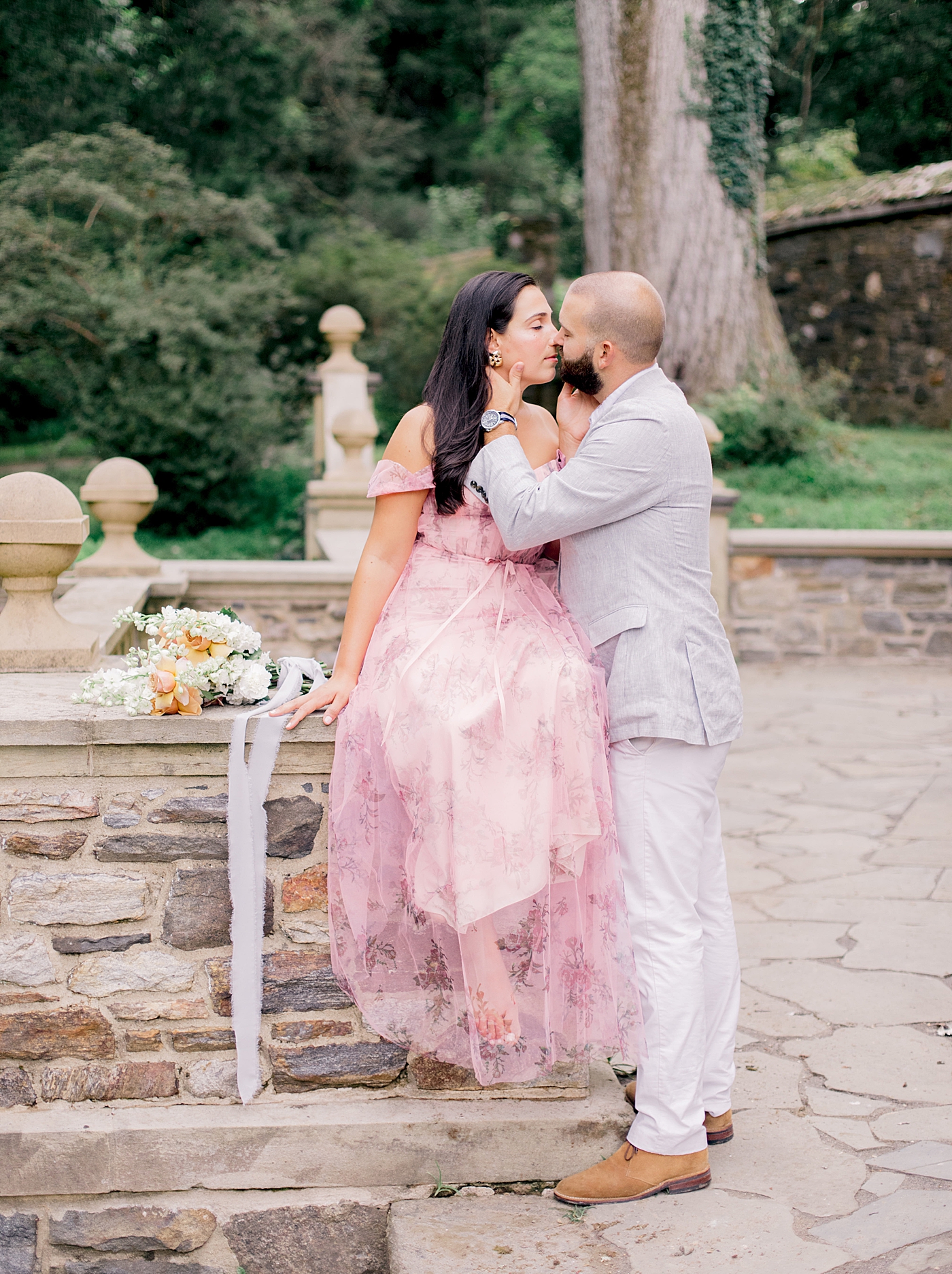Couple in formal attired kissing sitting on a rock wall | Styling and Planning Engagement Sessions with Hope Helmuth Photography