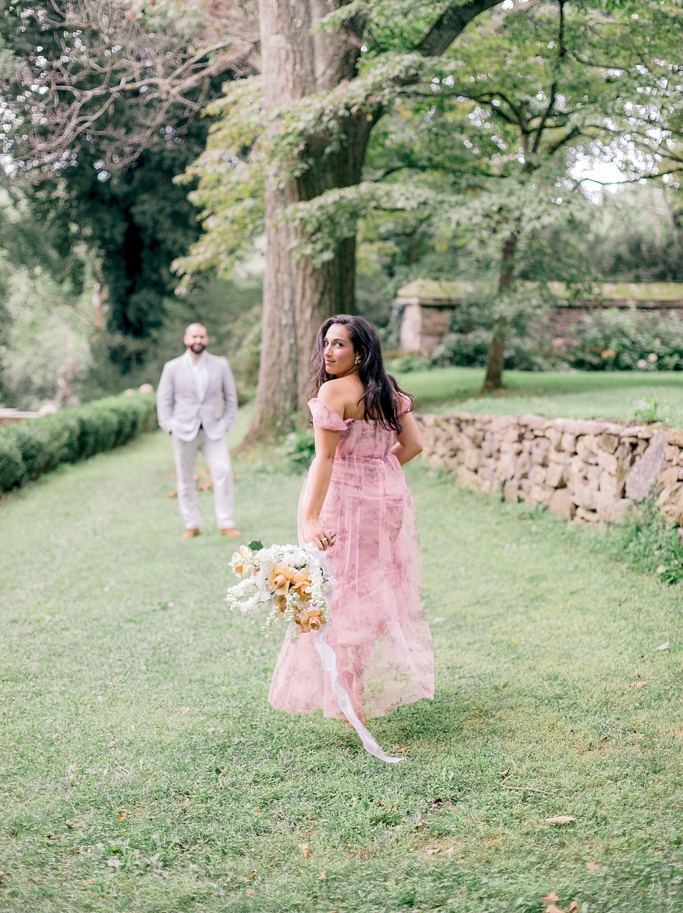 Woman in a pink dress holding a bouquet and walking toward her groom | Styling and Planning Engagement Sessions with Hope Helmuth Photography