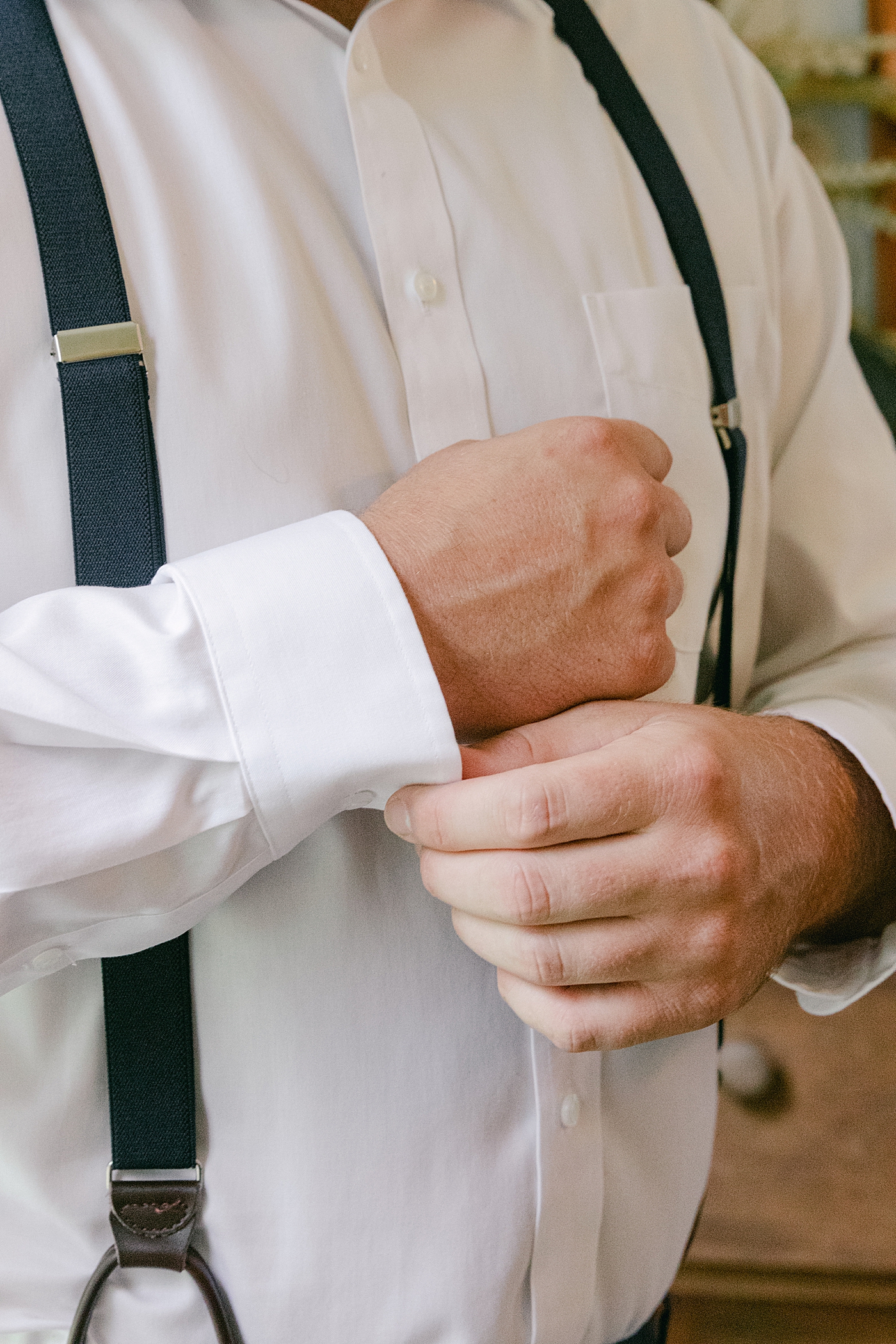 Groom buttoning his dress shirt | Image by Hope Helmuth Photography