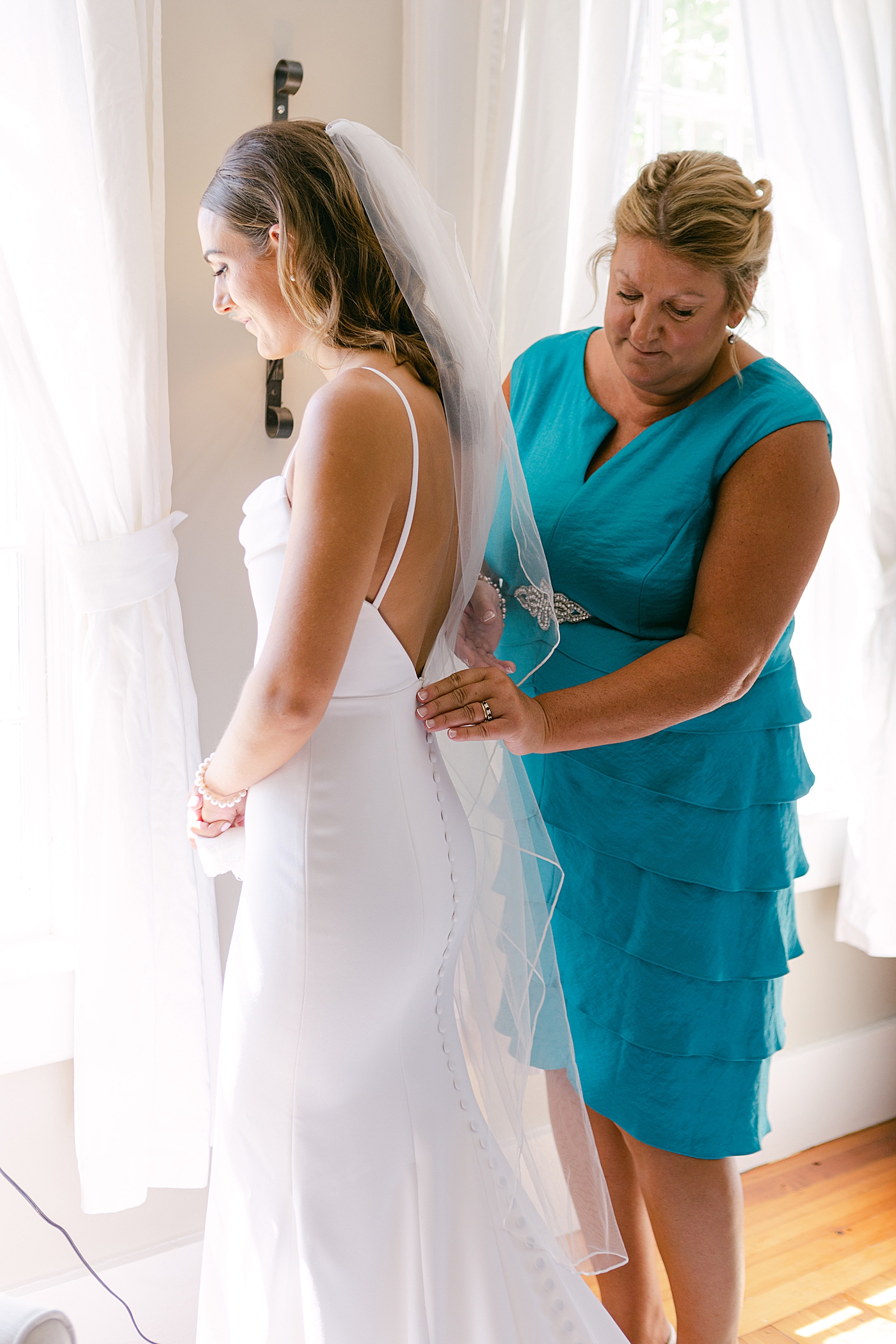 Bride being helped into her dress | Image by Hope Helmuth Photography