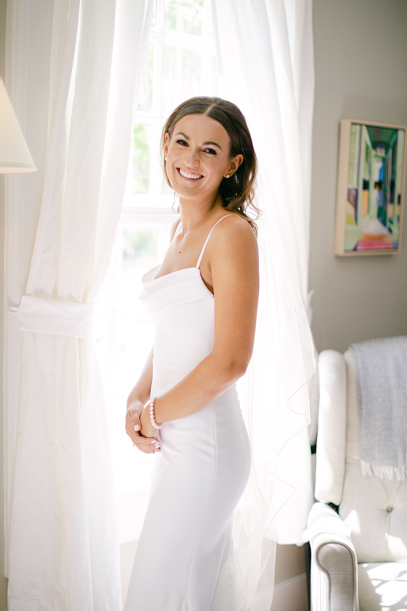 Bride smiling near a window | Image by Hudson Valley Wedding Photographer Hope Helmuth