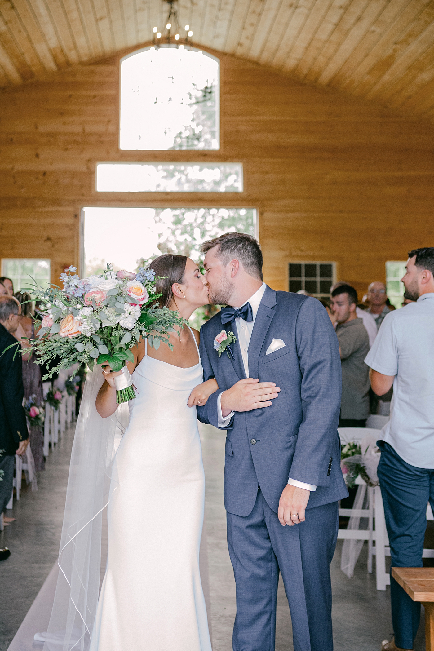 Bride and groom kissing walking down the aisle | Image by Hudson Valley Wedding Photographer Hope Helmuth