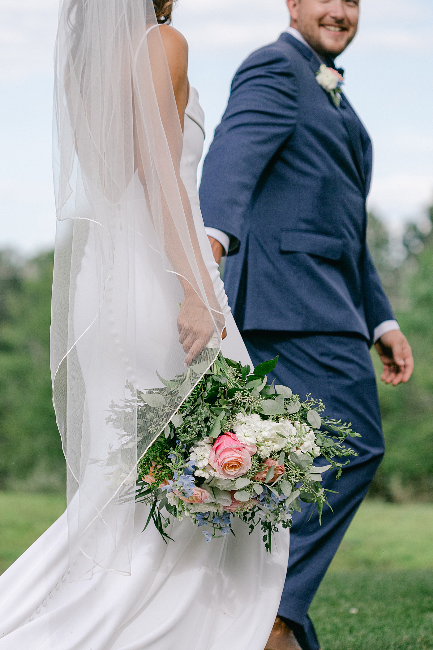 Detail of bride and groom holding hands and bouquet | Image by Hope Helmuth Photography