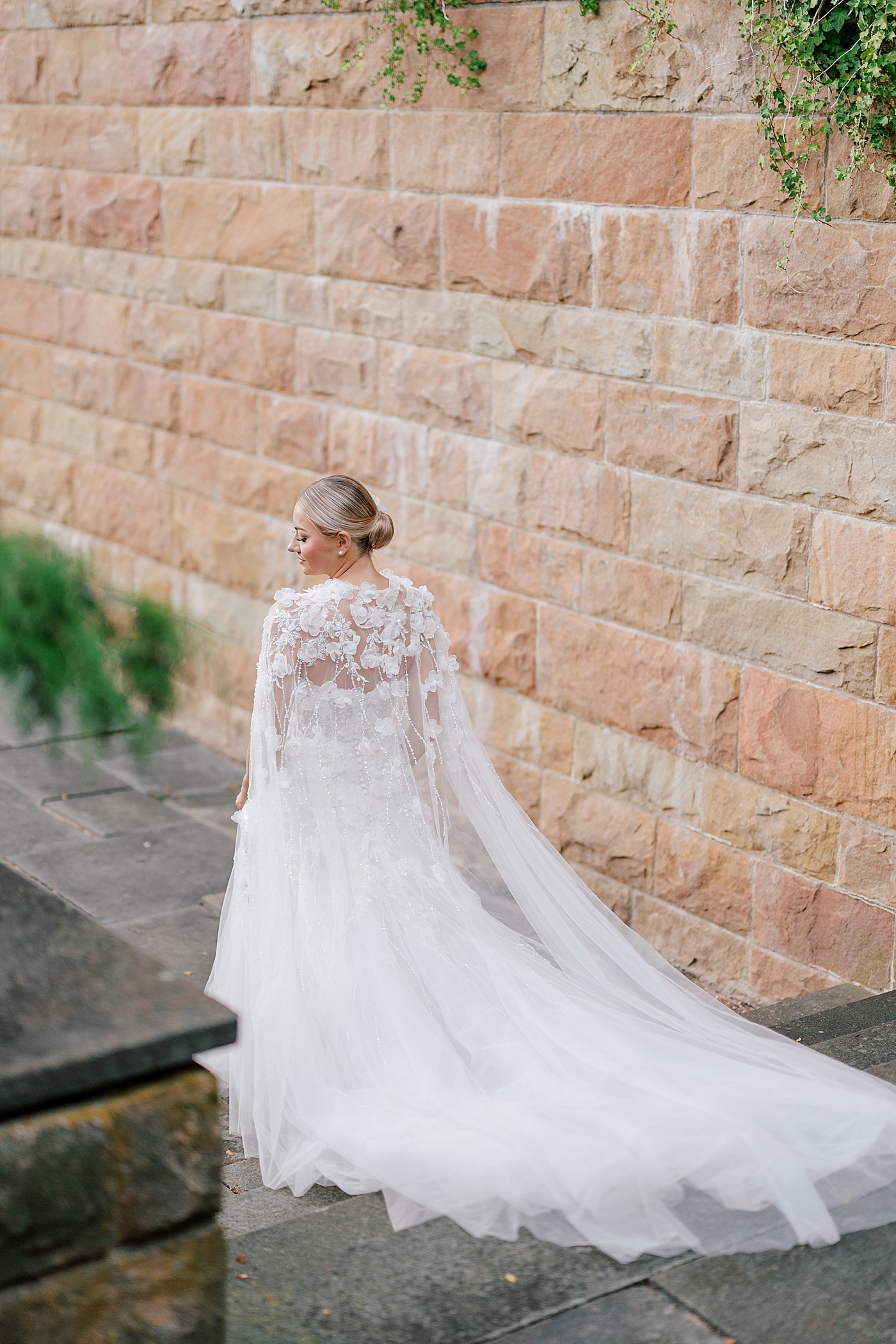 Bride with cape walking down stairs | Image by Hope Helmuth Photography