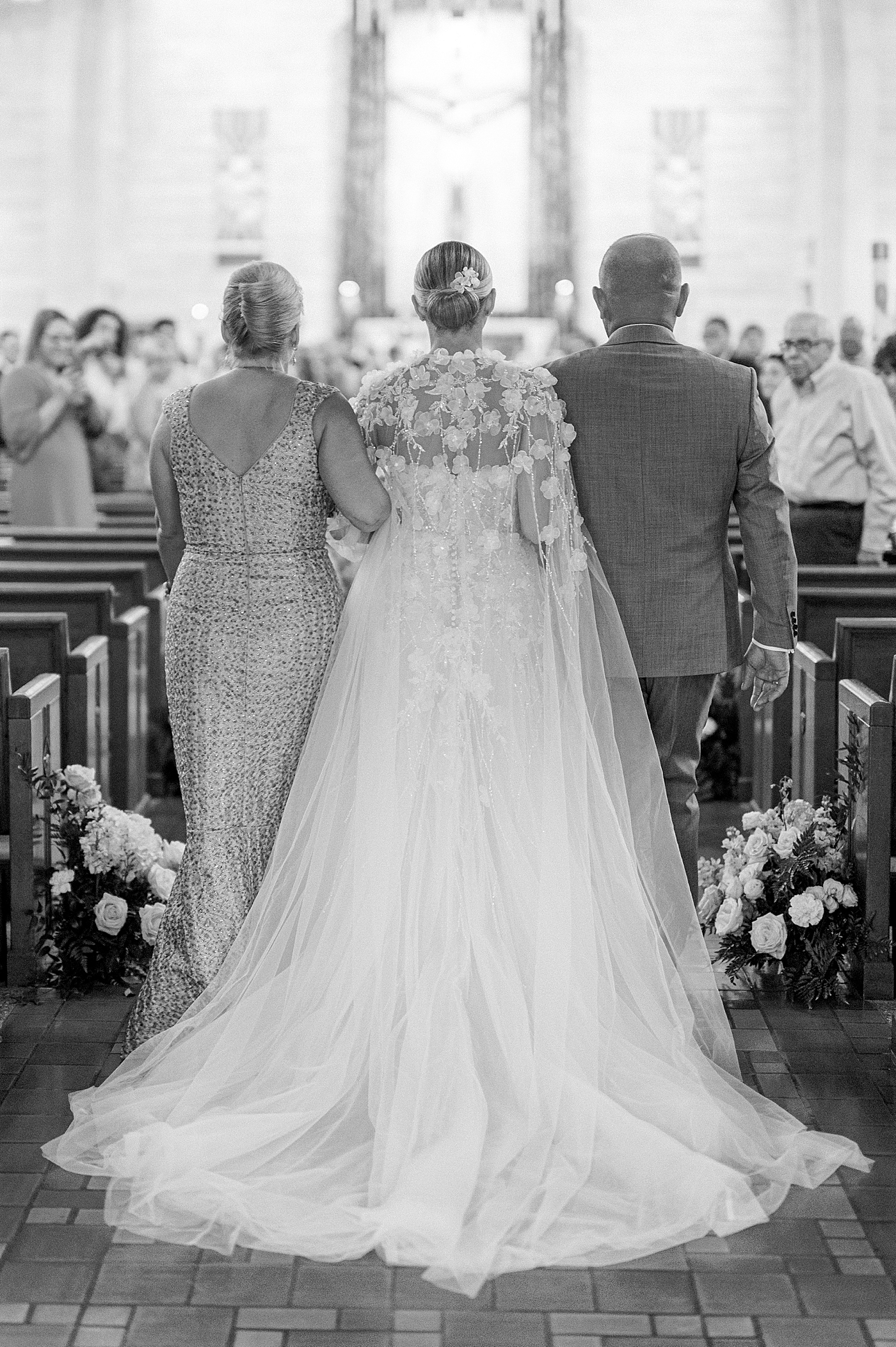 Black and white image of bride walking down the aisle | Image by Hope Helmuth Photography