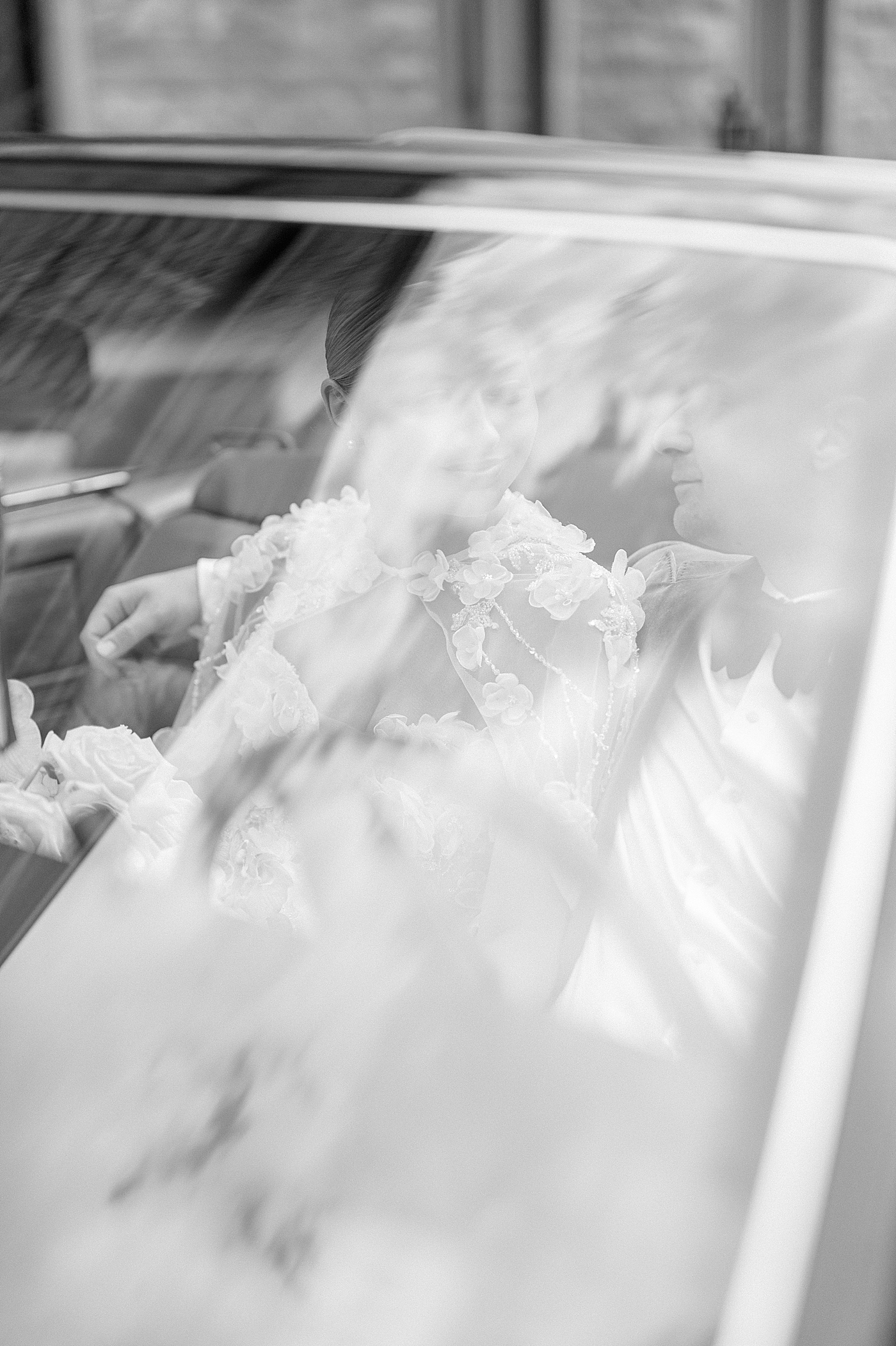 Black and white image of bride and groom behind windshield | Image by Hope Helmuth Photography