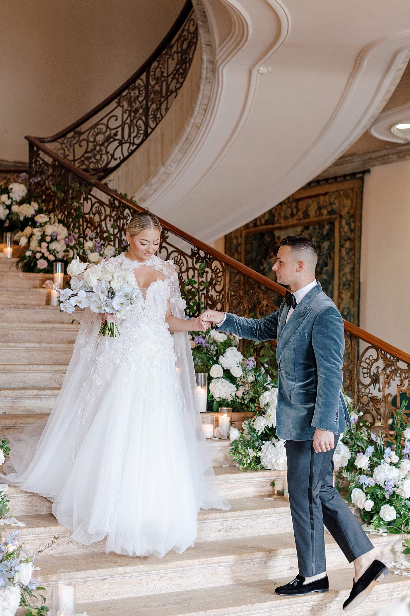 Groom helping bride down the stairs | Image by Hope Helmuth Photography