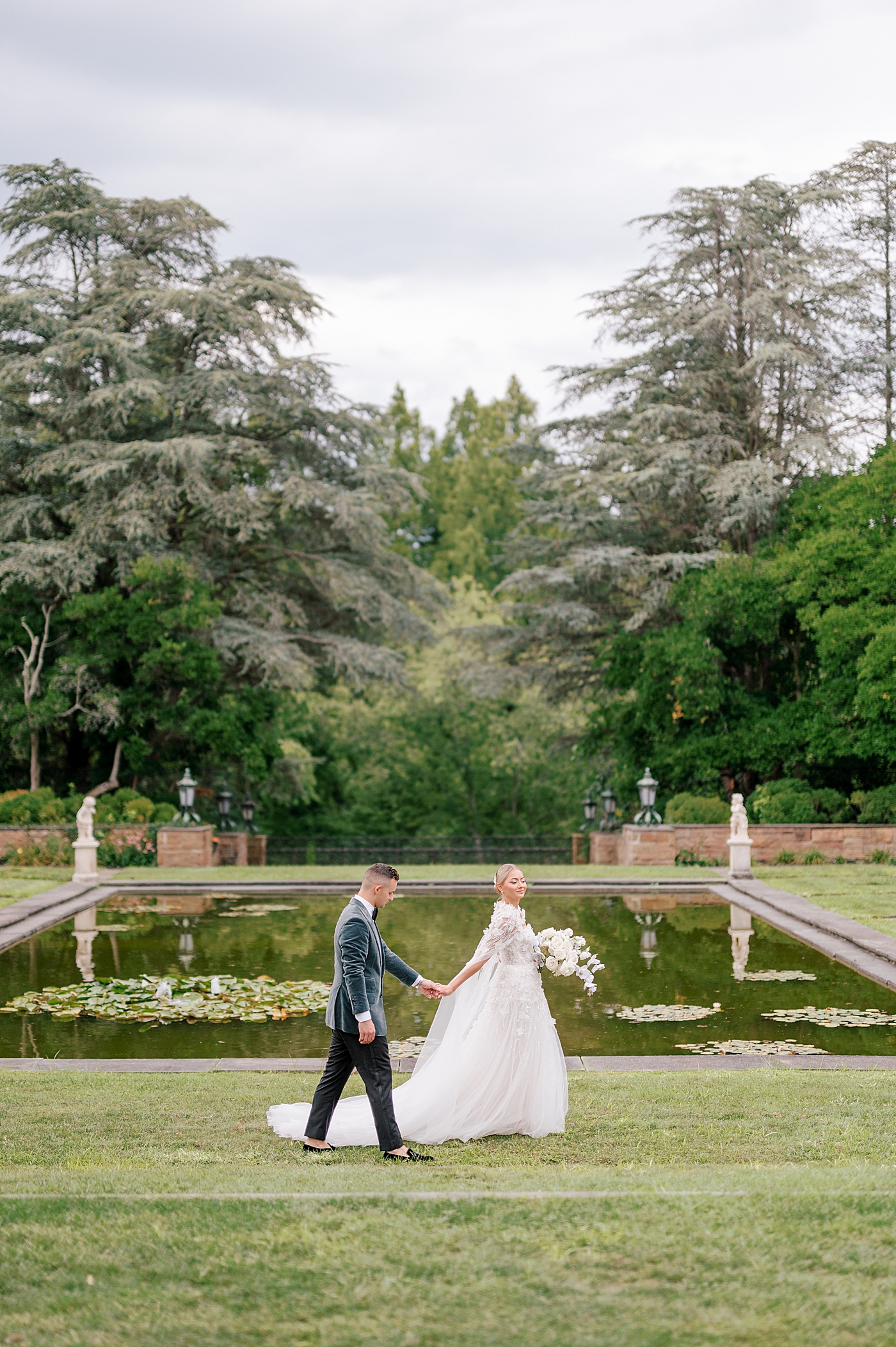 Bride and groom walking hand in hand through a garden | Image by Hope Helmuth Photography