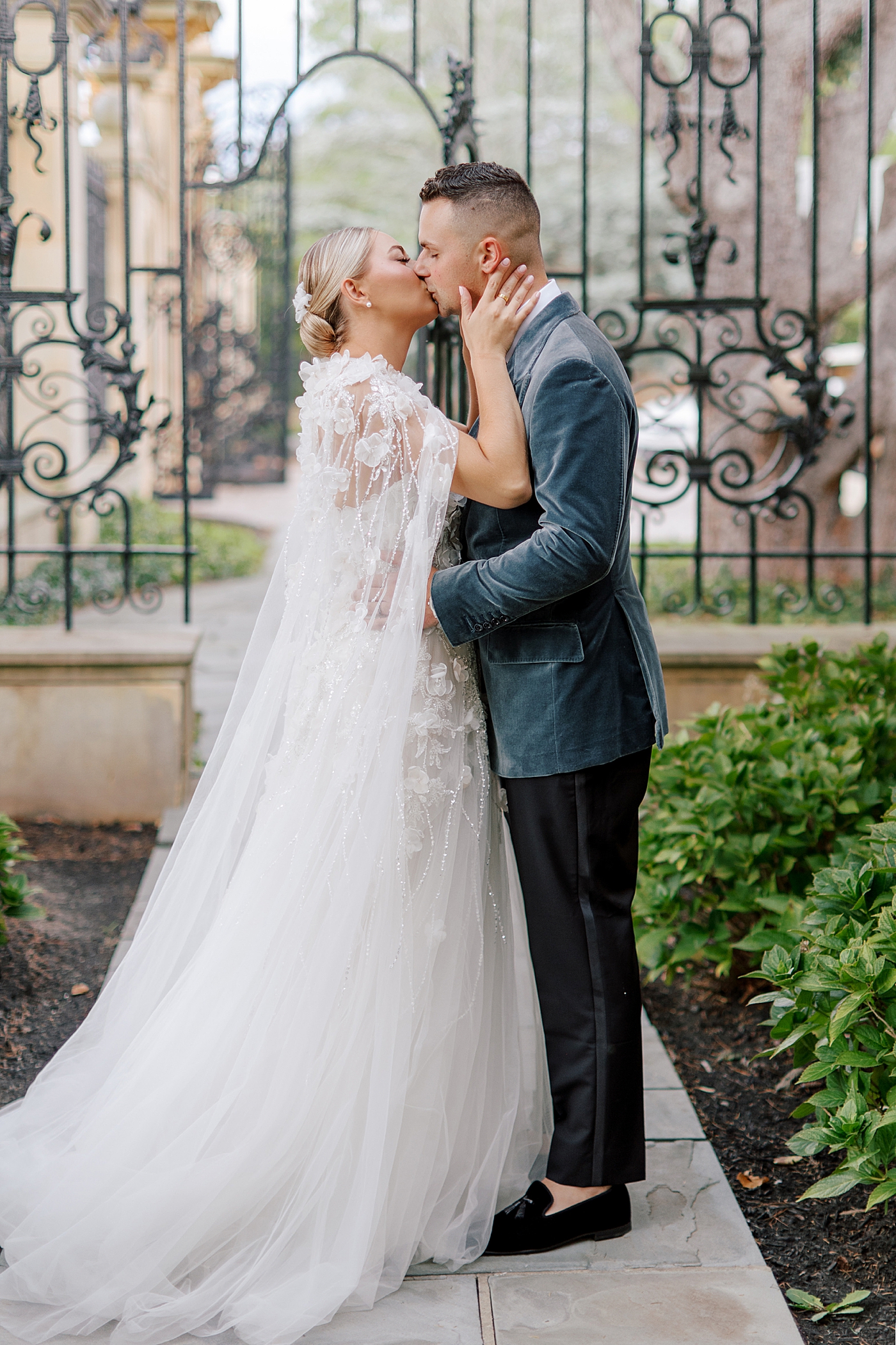 Bride and groom kissing in front of iron gate | Image by Hope Helmuth Photography
