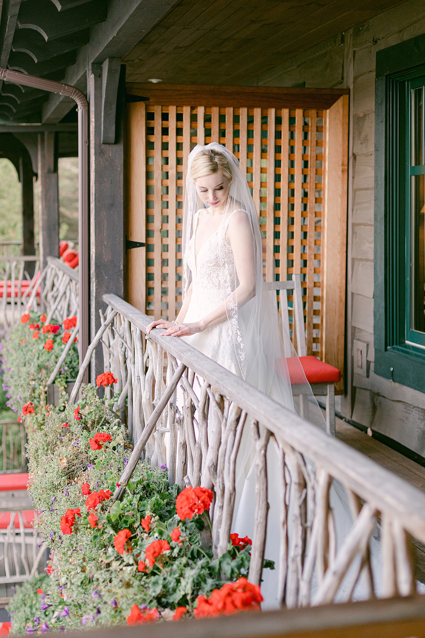 Bridal portraits on porch with red flowers | Image by Hope Helmuth Photography