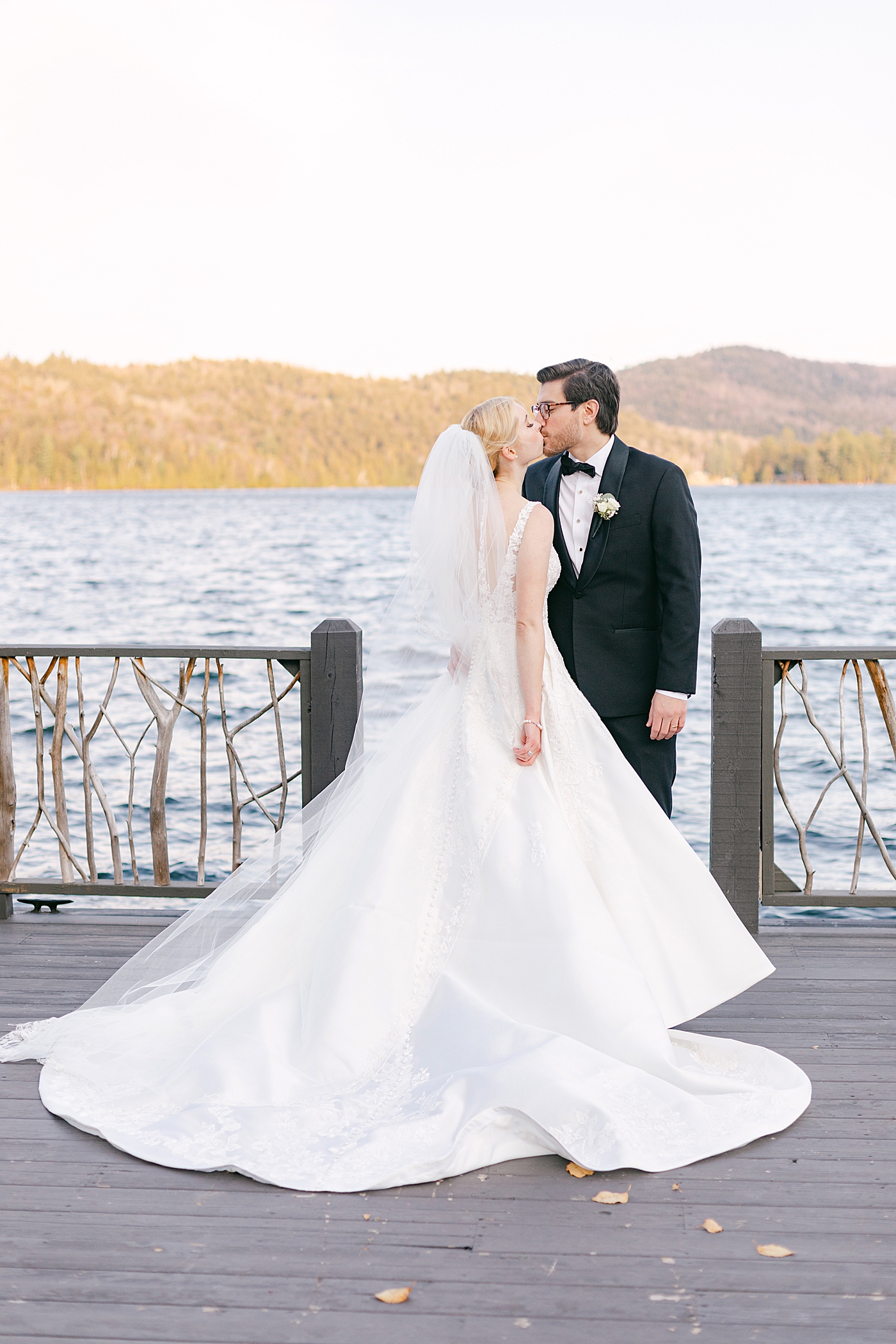 Bride and groom kissing on a dock during Lake Placid Lodge Wedding | Image by Hope Helmuth Photography
