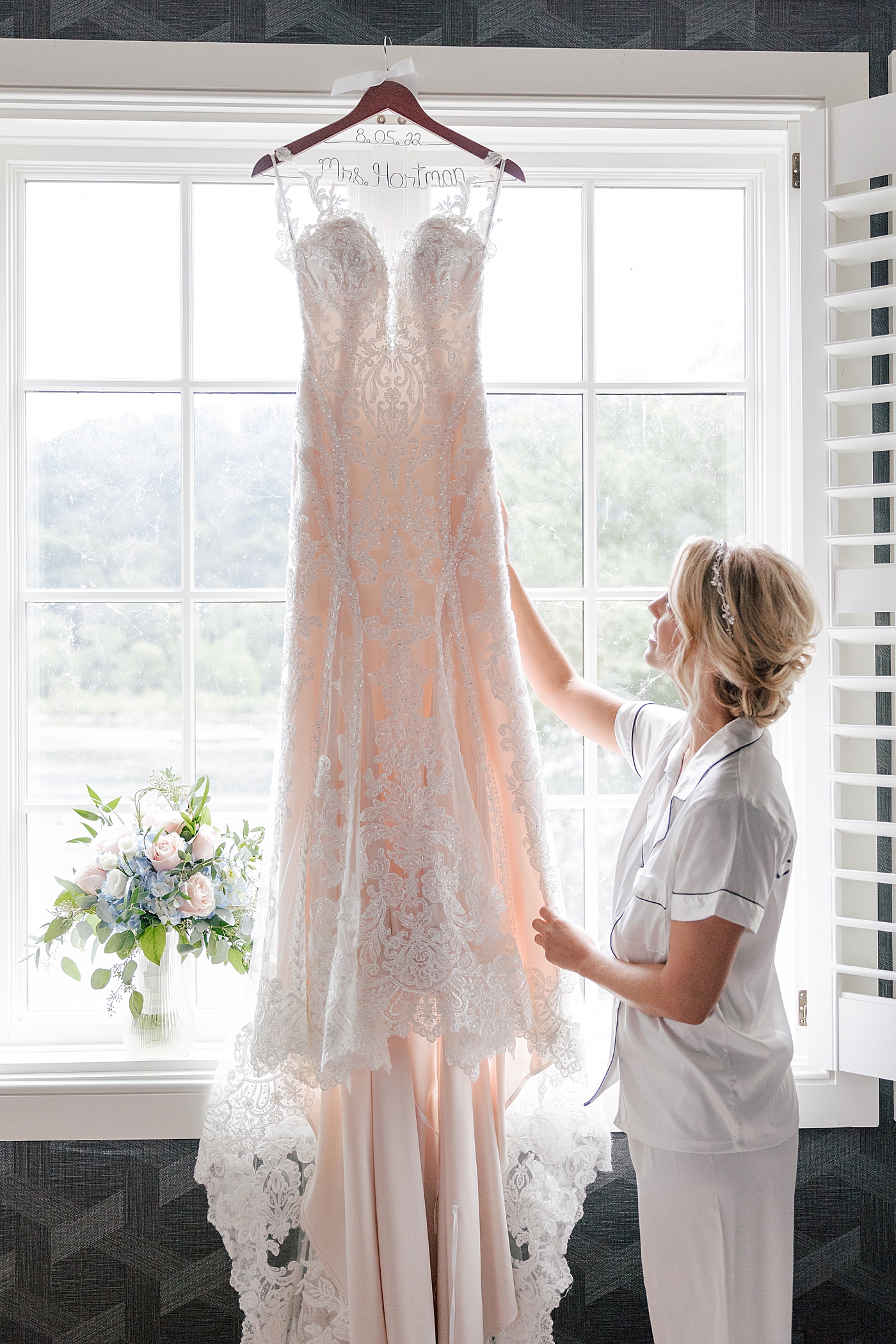Bride adjusting her gown on a hanger during River House Odette's Wedding | Image by Hope Helmuth Photography