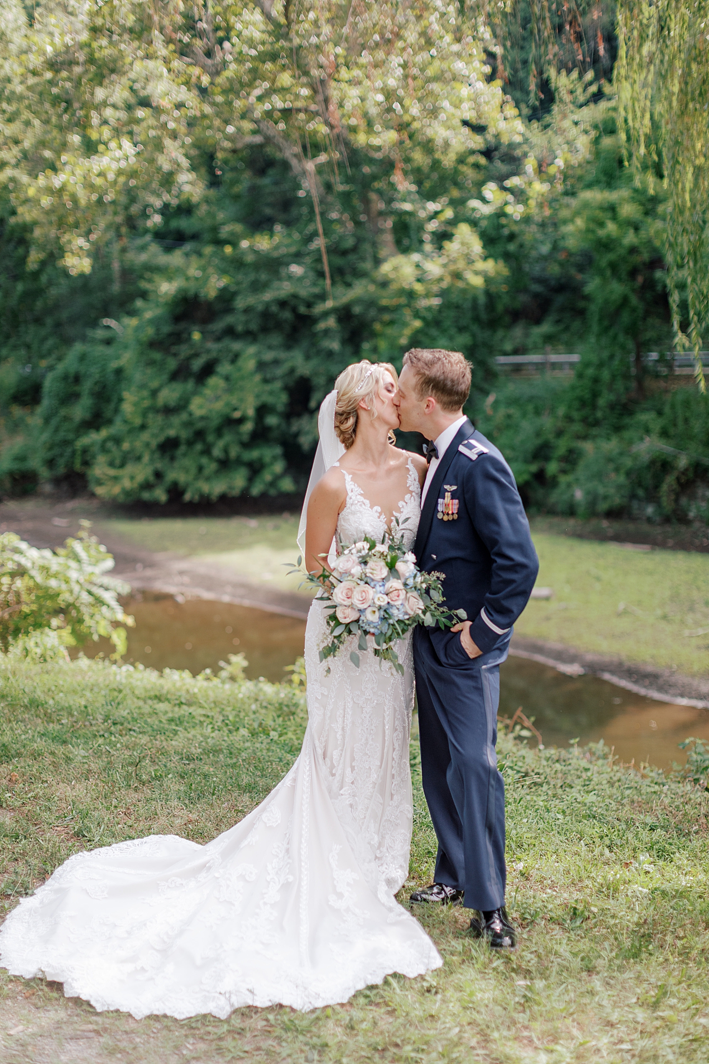 Bride and groom kissing near a creek | Image by Hope Helmuth Photography