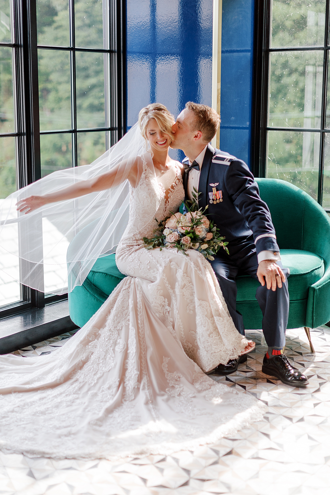 Bride and groom sitting on a green sofa | Image by Hope Helmuth Photography