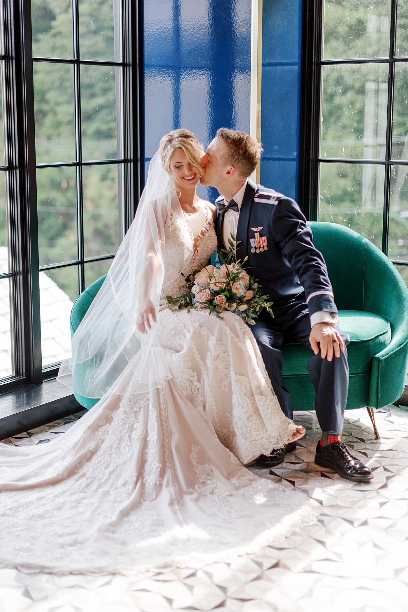 Bride and groom sitting on a green sofa during River House Odette's Wedding | Image by Hope Helmuth Photography