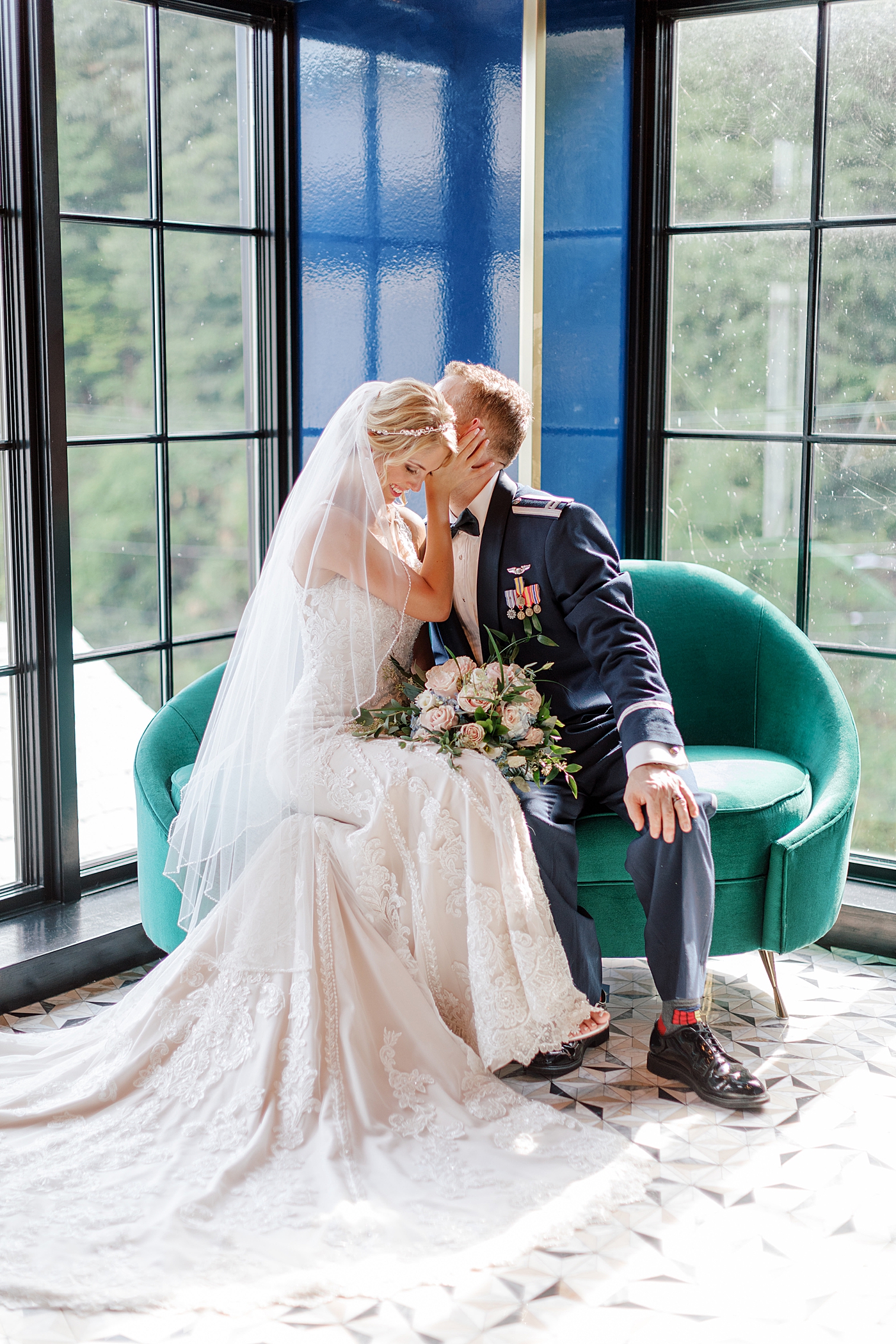 Bride and groom sitting on green sofa during River House Odette's Wedding | Image by Hope Helmuth Photography