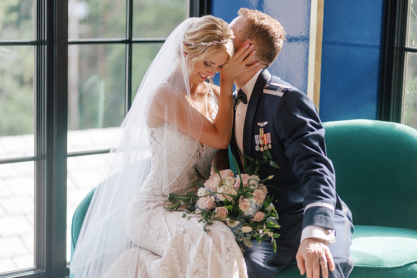 Bride and groom sitting on a green couch | Image by Hope Helmuth Photography