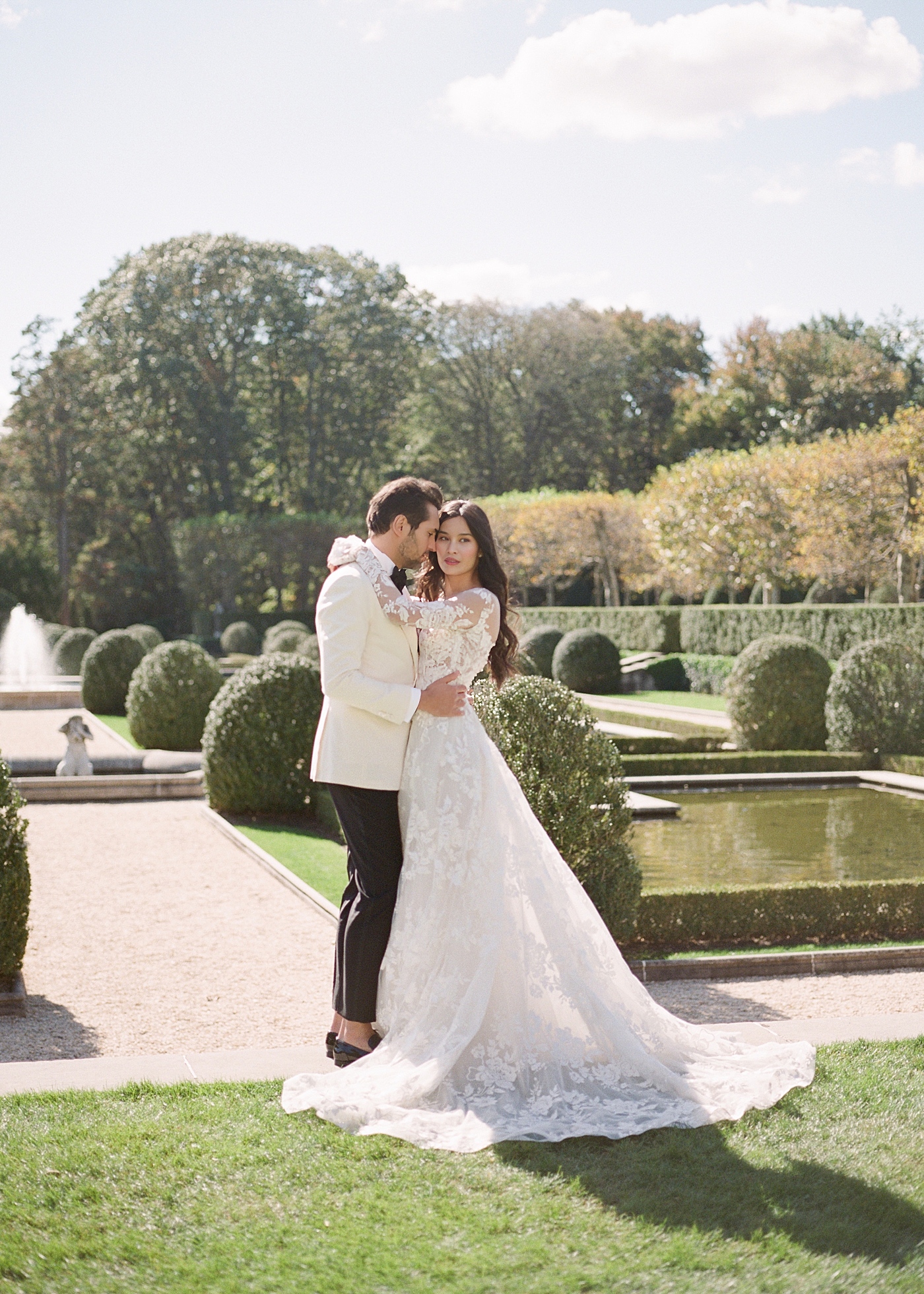 Image of a bride and groom embracing in a European garden during Oheka castle wedding | Image by Hope Helmuth Photography