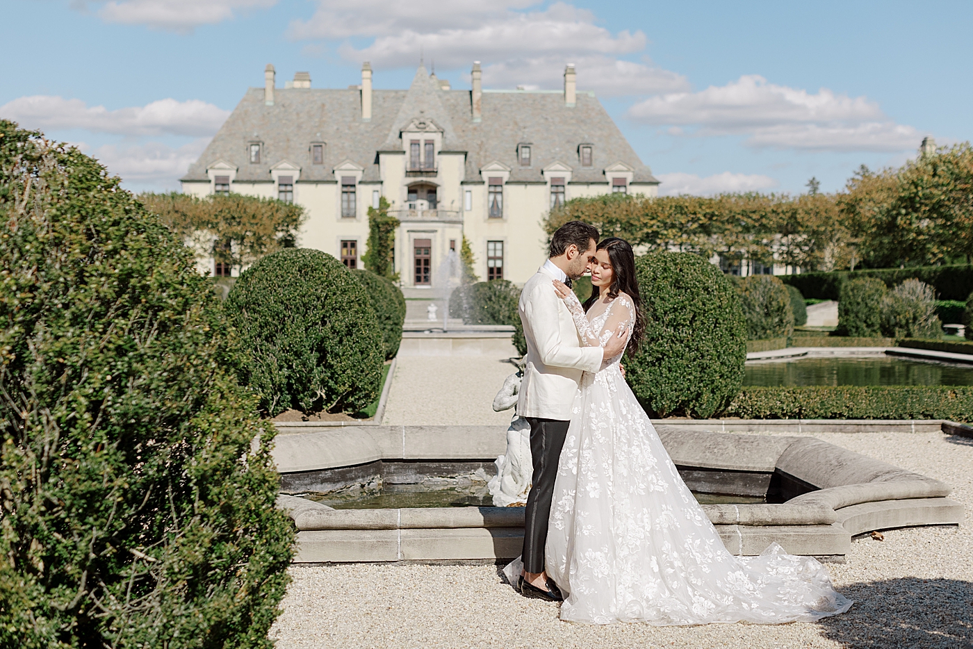 Image of a bride and groom embracing in a European garden during Oheka castle wedding | Image by Hope Helmuth Photography